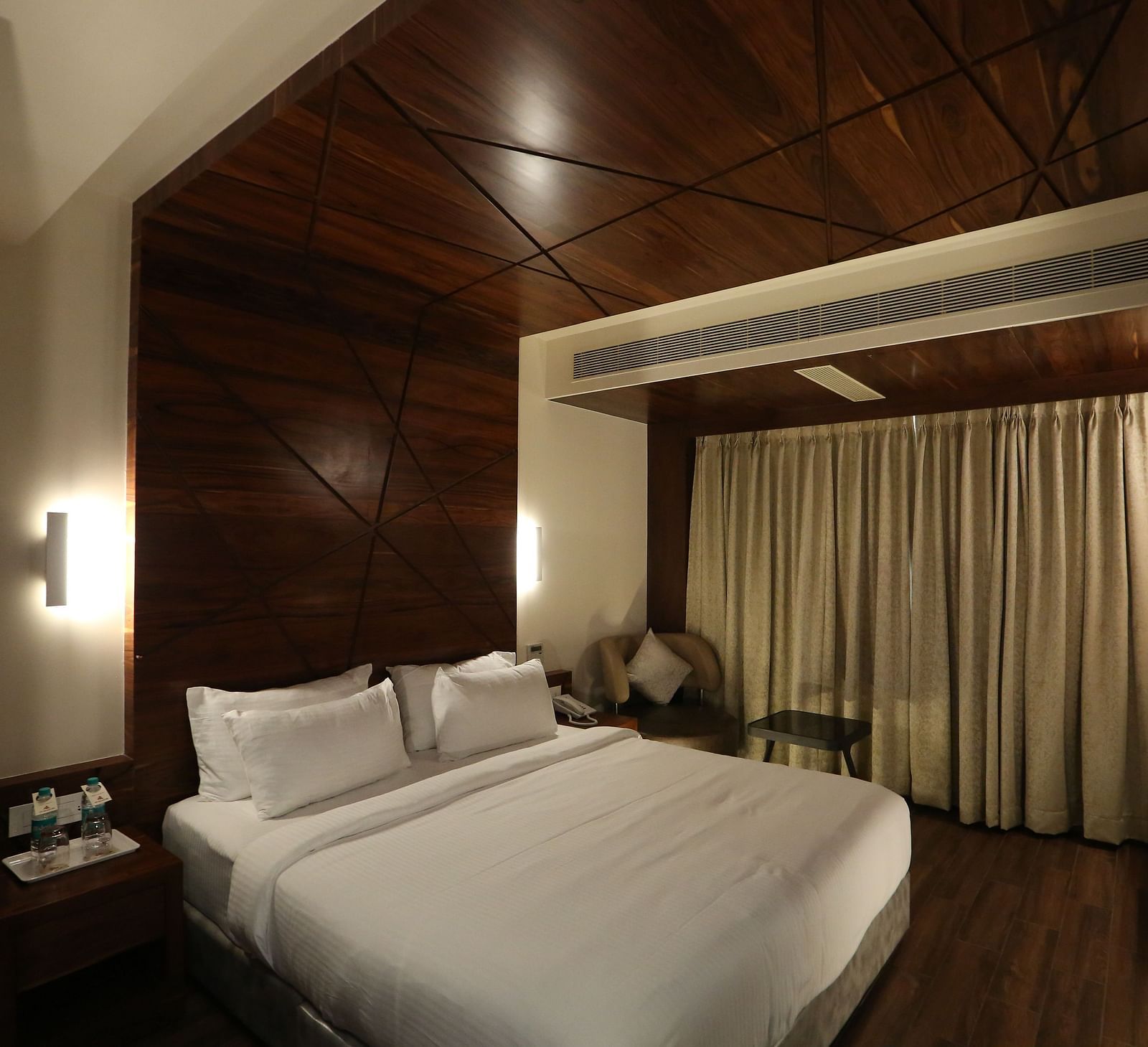 Premium Suite featuring a king size bed, bedside tables, lamps, and dark wood panelling - TGI SPS Grand, Coimbatore