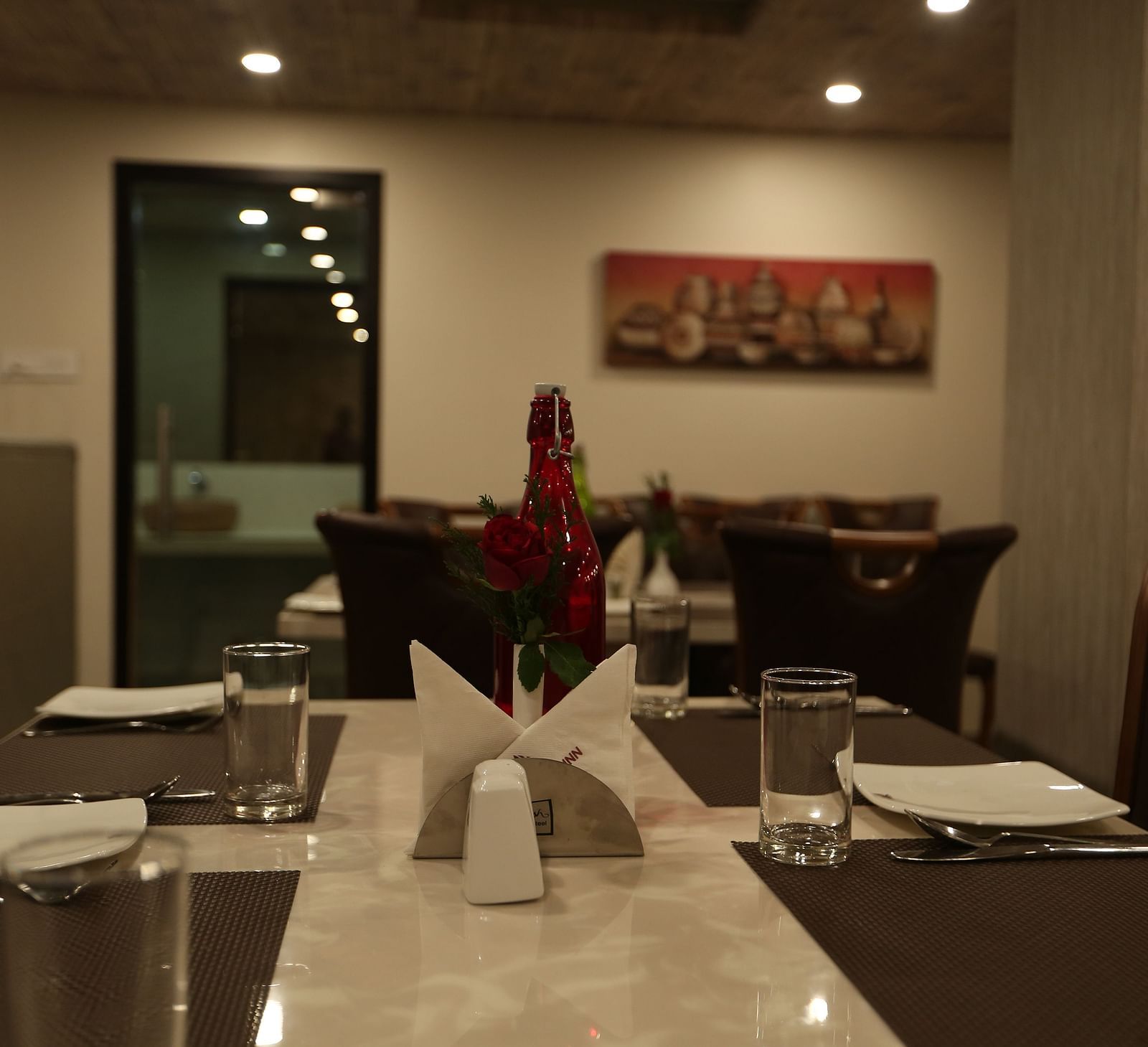 A well-lit restaurant area with dark wood furniture and table settings  - TGI SPS Grand, Coimbatore