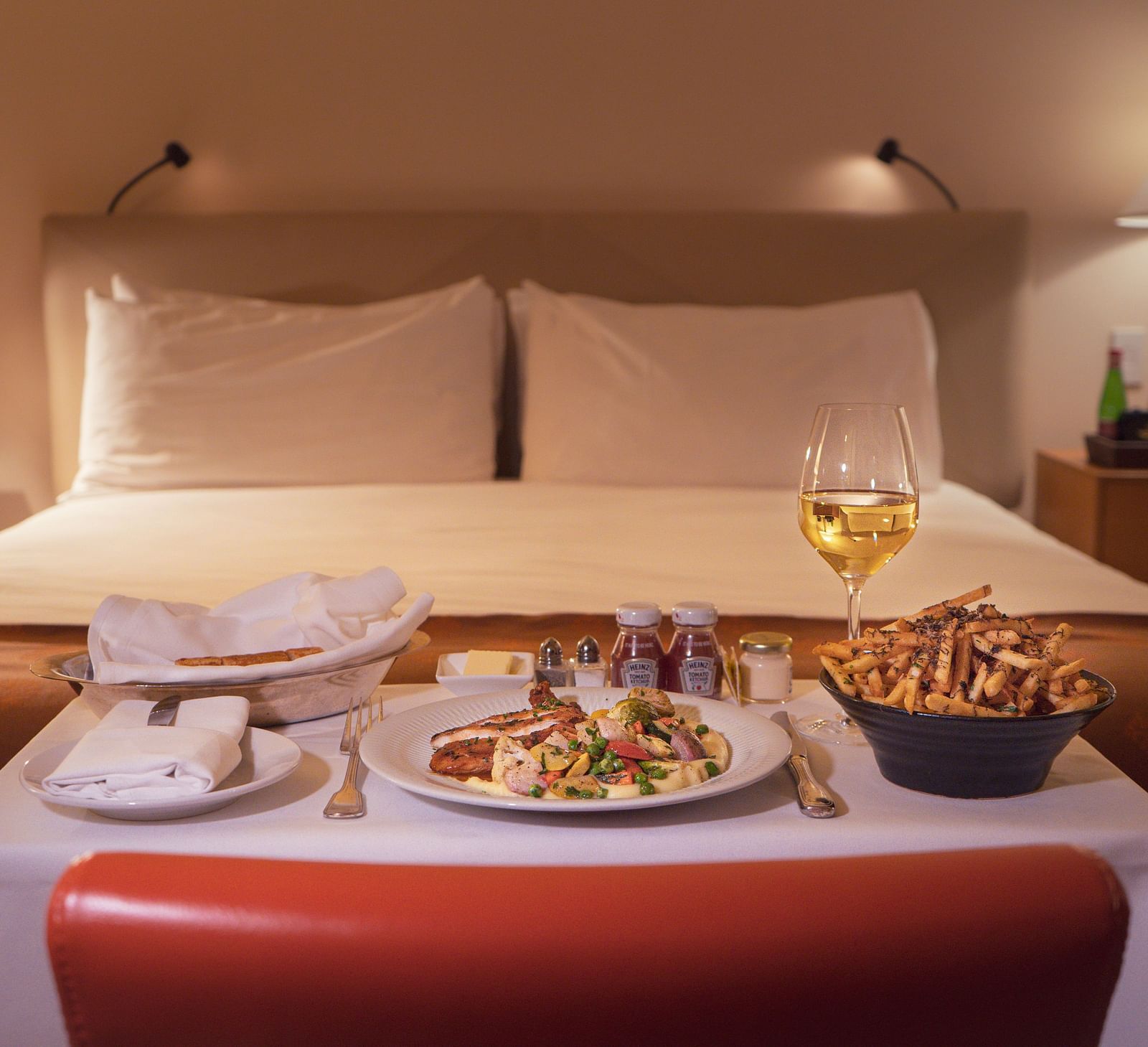 Many items on a table that was served as room service with a double bed in the background