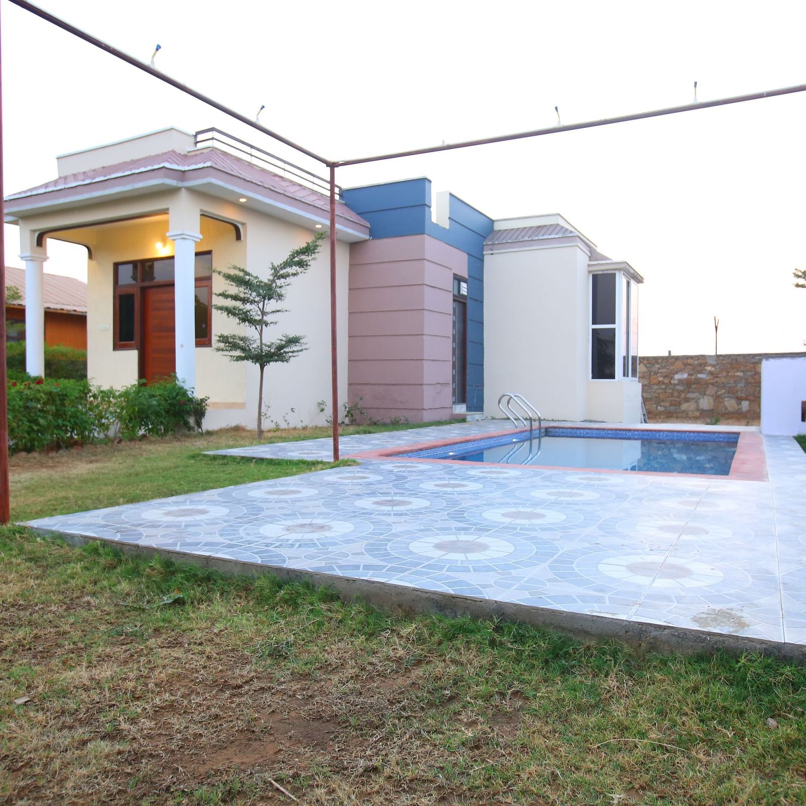 Facade of the Party Villa with Pool at Aanandam Resort & Spa, featuring plants lining the pathway and a swimming pool beside the building