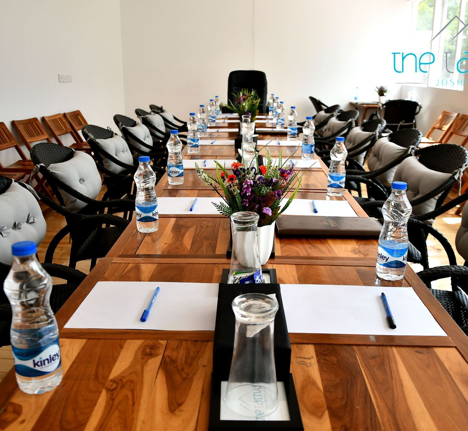 front view image of the conference hall featuring the expansive table decorated with flowers and stationery at the tattva, joshimath