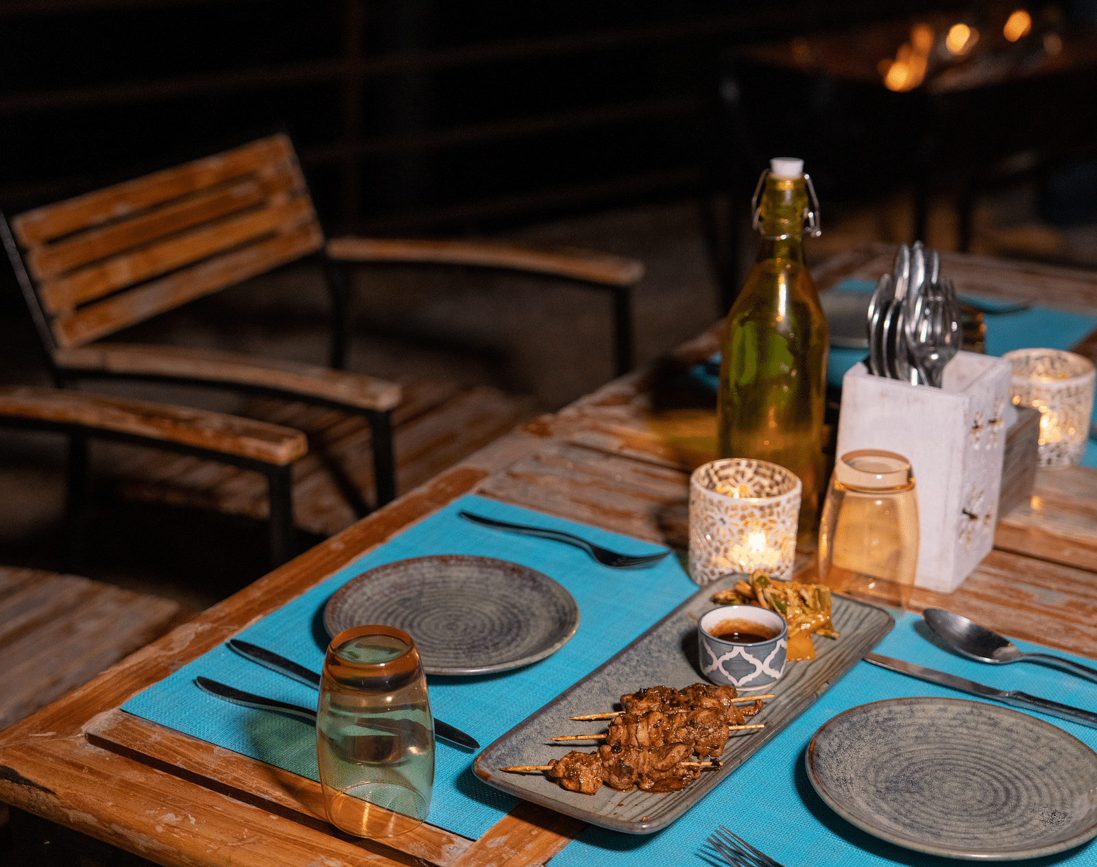 An outdoor dining area in the evening with a table set with food, drinks, and cutlery at BluSalzz Escapade Resort, Lansdowne