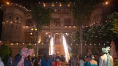 Guests are gathered outside the illuminated Tijara Fort-Palace - 19th Century, Alwar at night, with a red carpet leading up to the building where sparklers are going off.