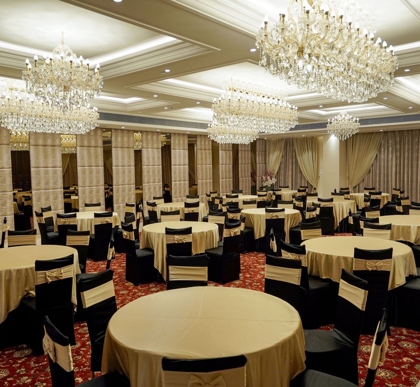 Corner view shot of the ballroom at M2 Square by Monday Premium featuring various tables surrounded by black coloured chairs.