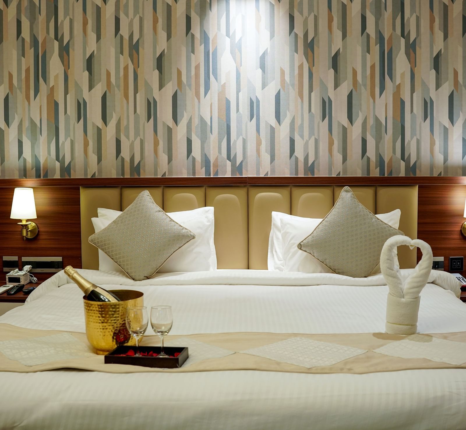Front view shot of a double bed featuring an ice bucket with a bottle of champagne kept on the bed in the Premium Room at M2 Square by Monday Premium.