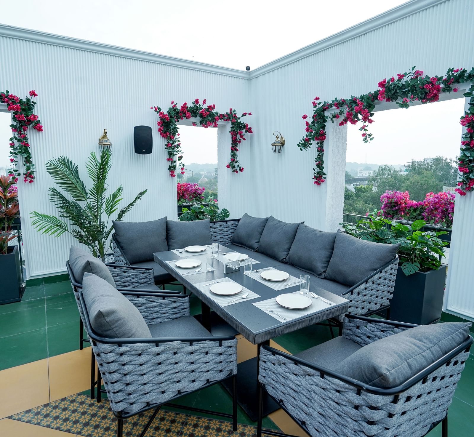 A wide angle shot of a dining table with a capacity of 6 people featuring a white coloured wall behind it at the Sky Roof during the day at M2 Square by Monday Premium.
