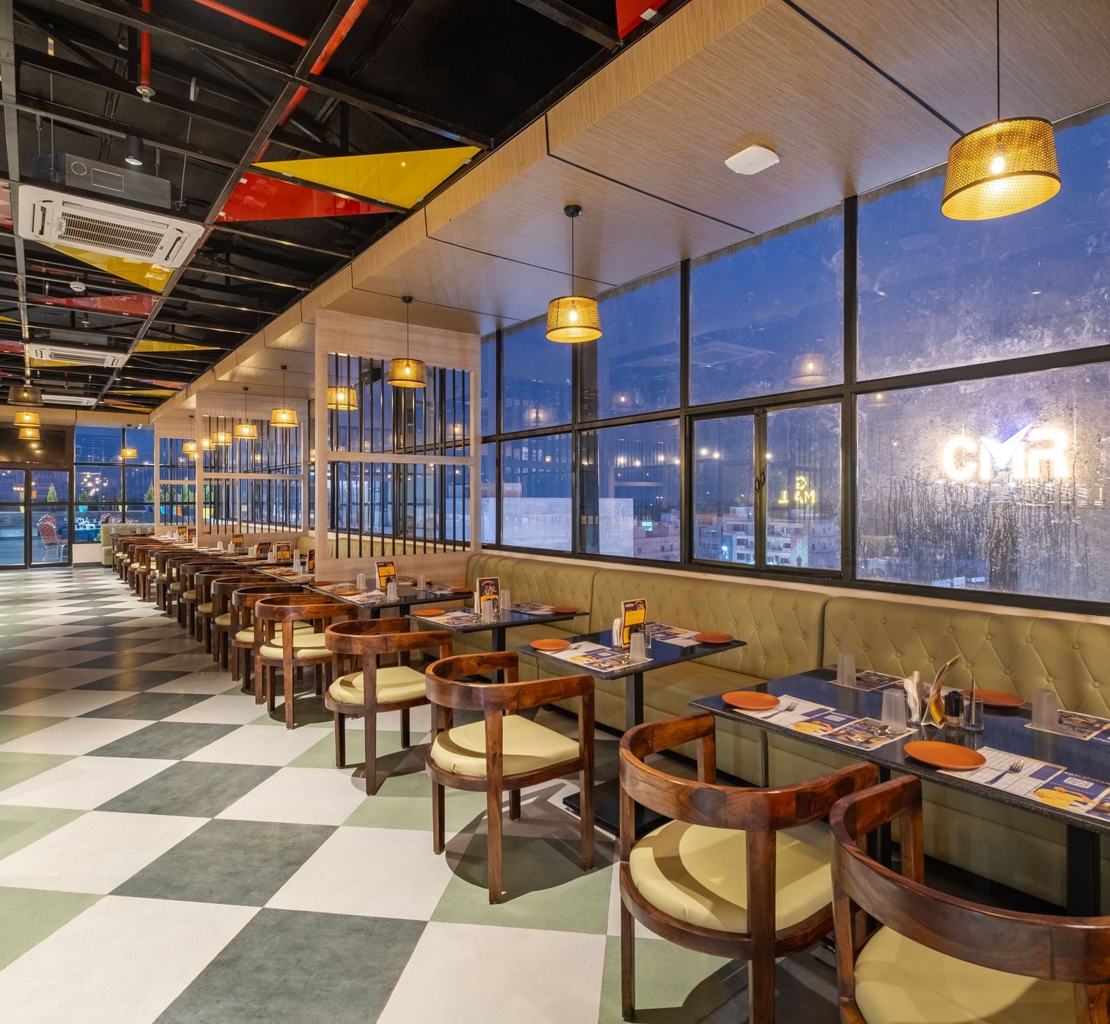 Bright dining hall at Monday Hotels Amalapuram Heights with large glass windows.