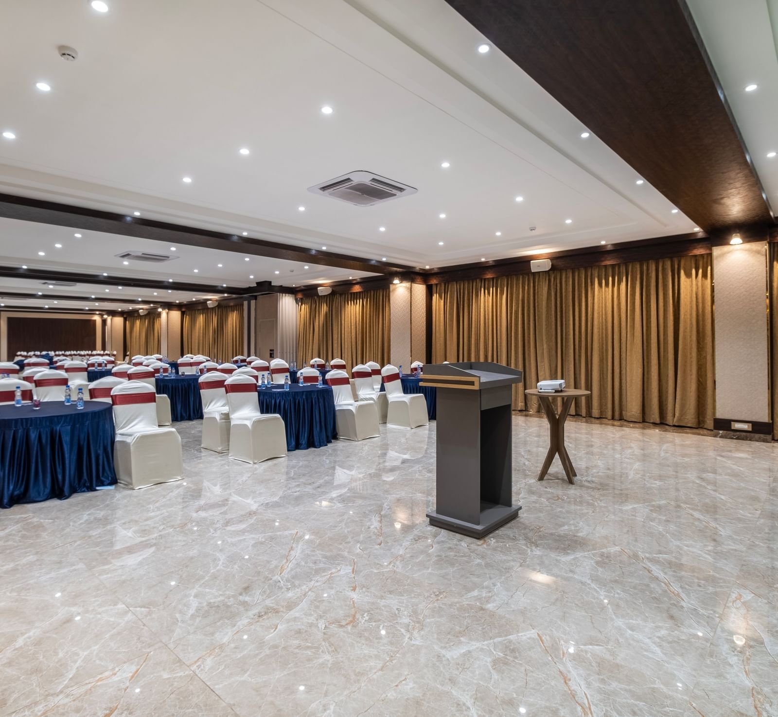 Event hall at Monday Hotels Amalapuram Heights arranged with cluster style seating and stage podium.