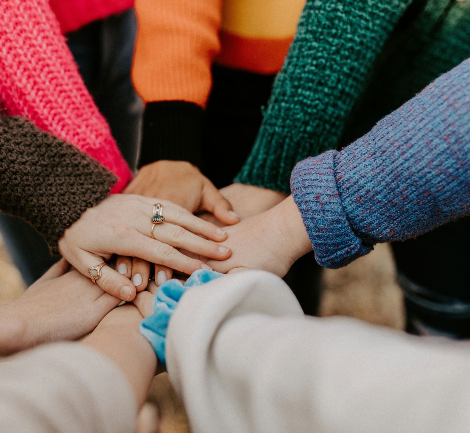 A group of people stacking their hands on top of each other in a gesture of unity and teamwork.