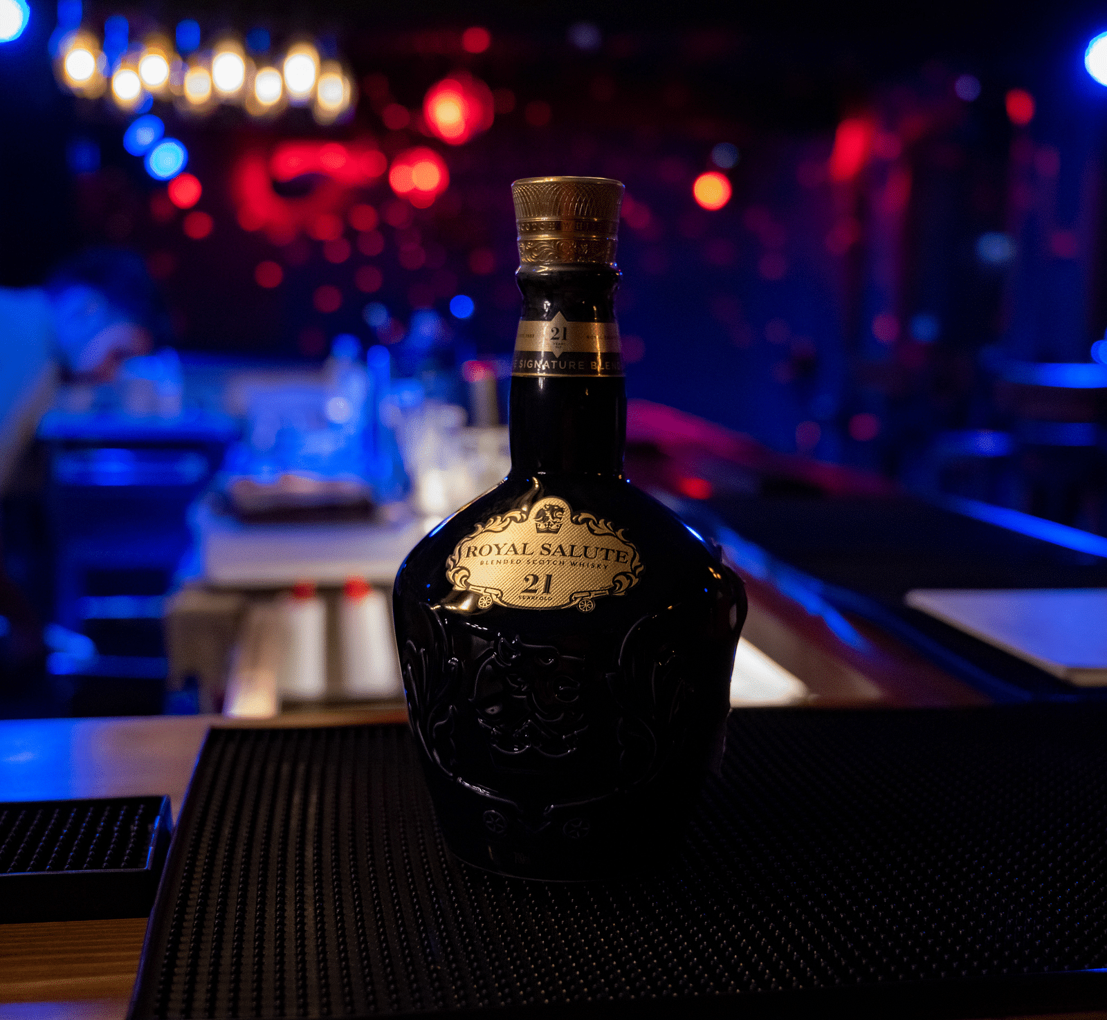 image of a beautiful liquor bottle kept in a dimly lit bar with blue lights - The Tattva Boutique Resort