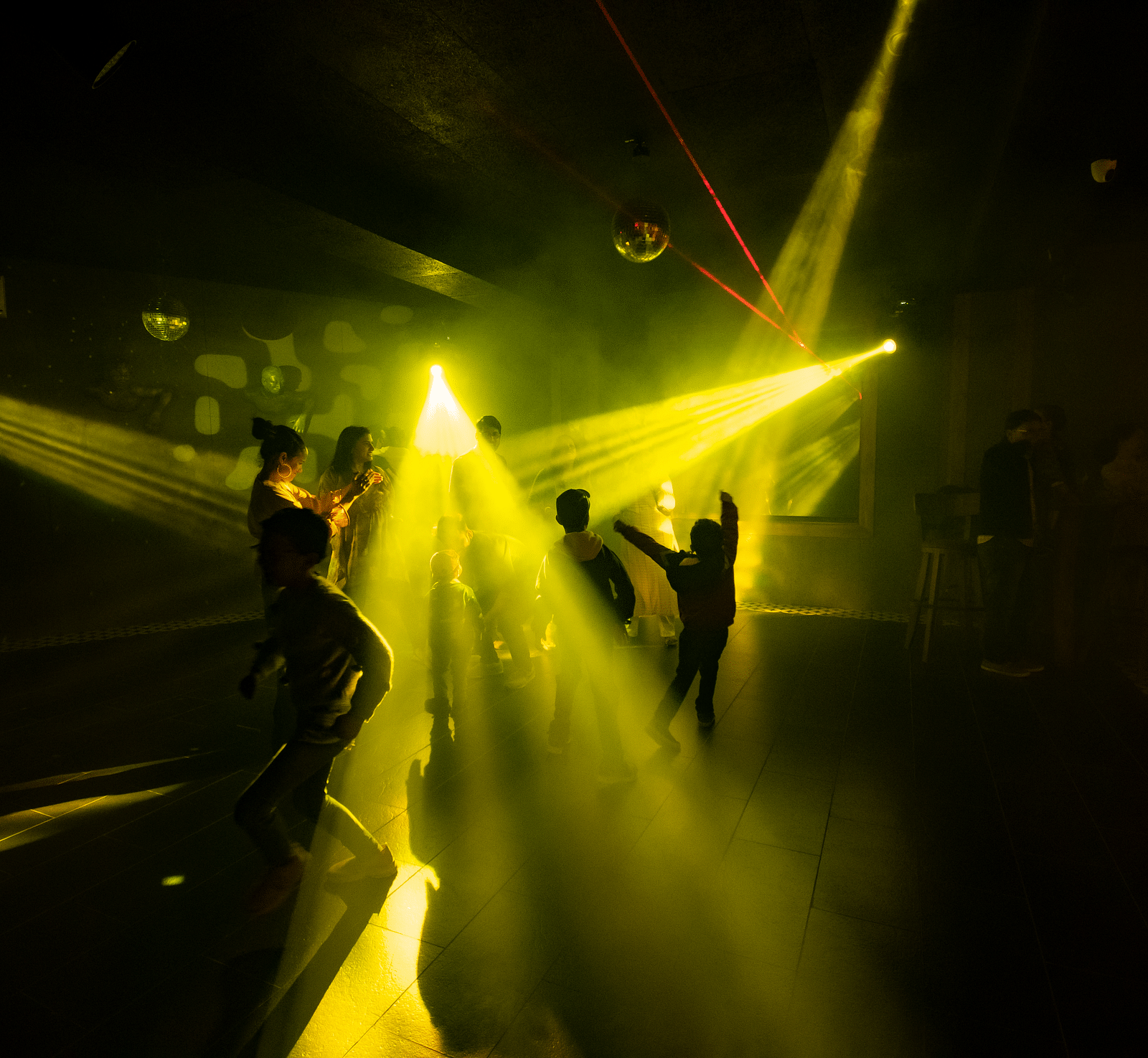 image of people dancing on the dance floor with yellow beam lights flashing around - The Tattva Boutique Resort