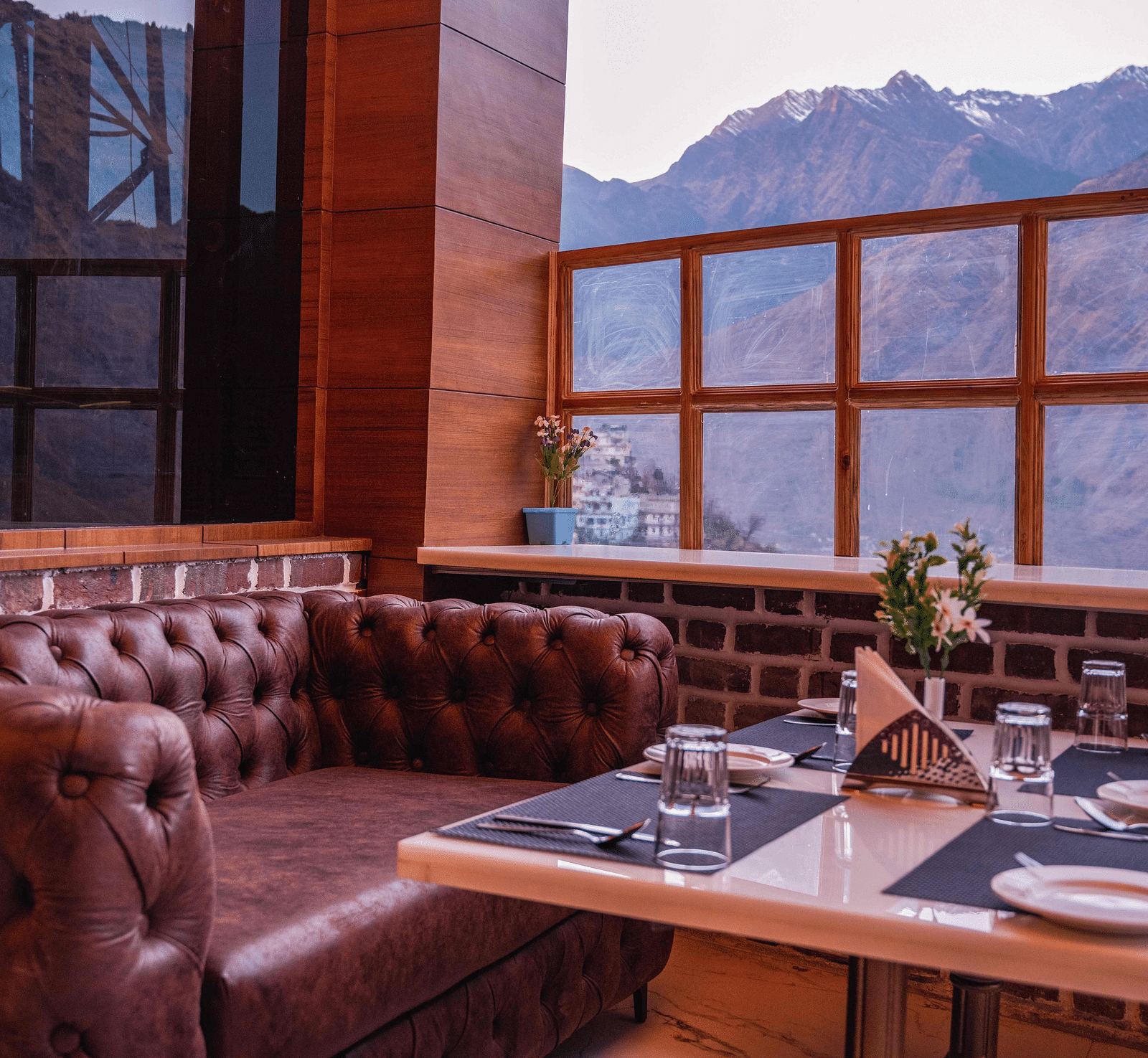 image of a maroon leather sofa with a dining table in front of it at the alpenrose restaurant - the tattva boutique resort