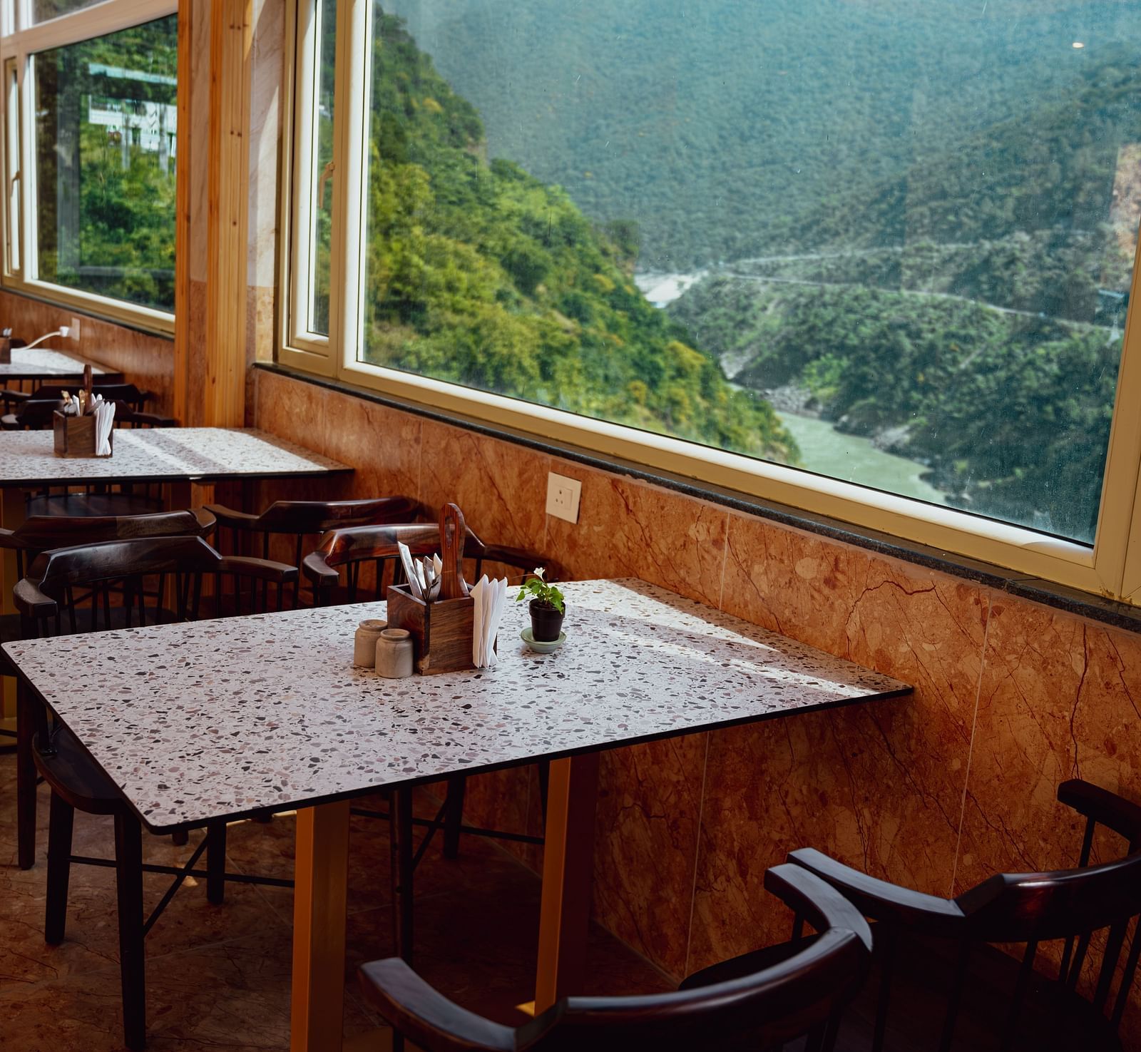 Image of the dining area by the window overlooking the mountains and the river | The Tattva Devprayag