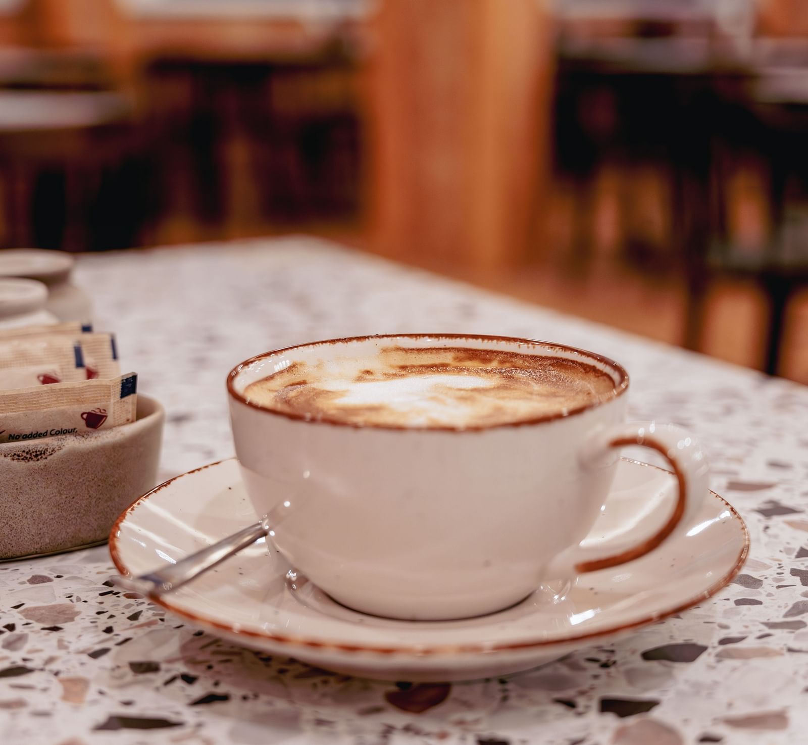 Image of a cup of coffee with sugar packets on the table | The Tattva Devprayag