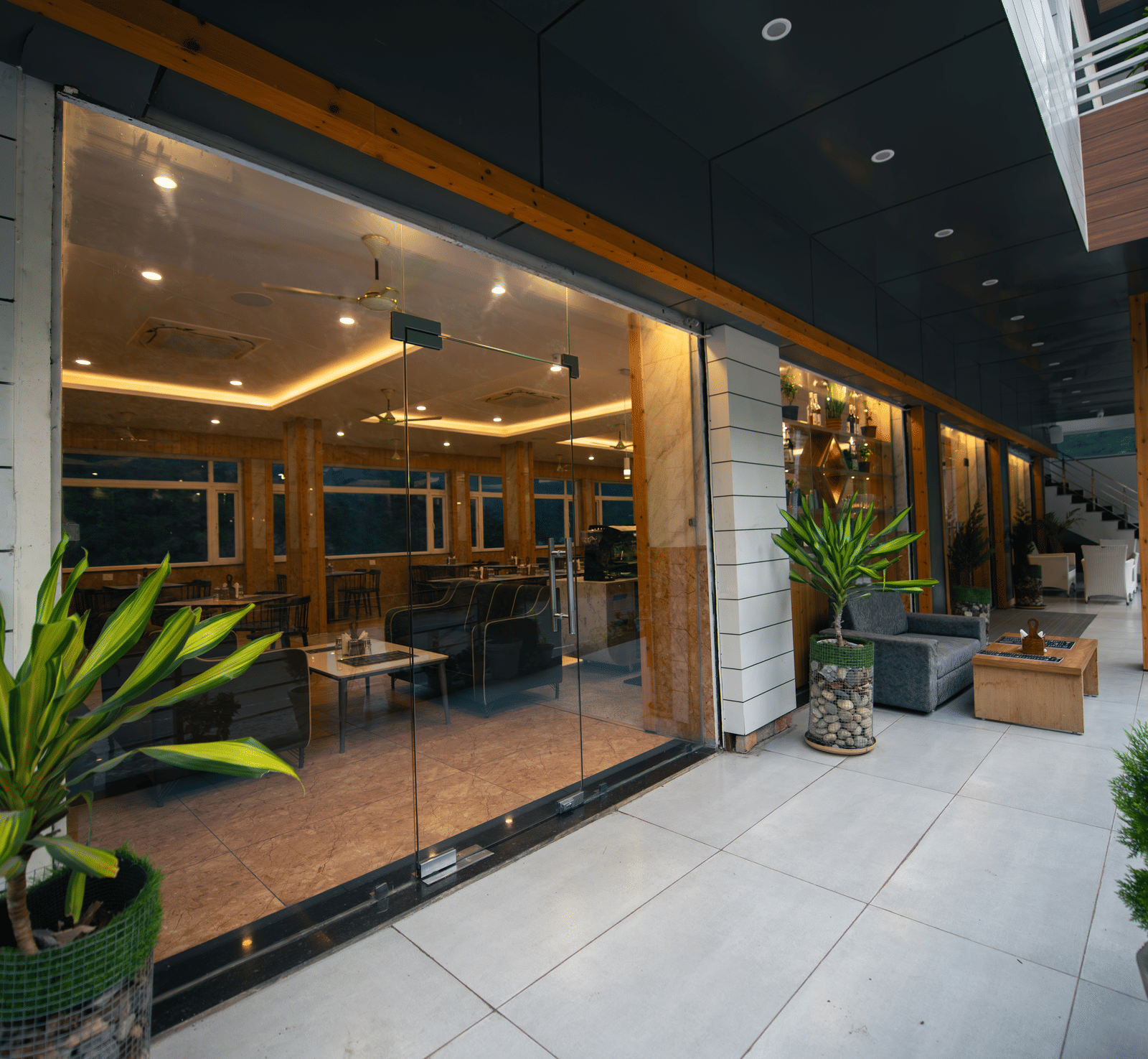 An entrance to the restaurant at The Tattva Devaprayag with big glass windows and some plants.