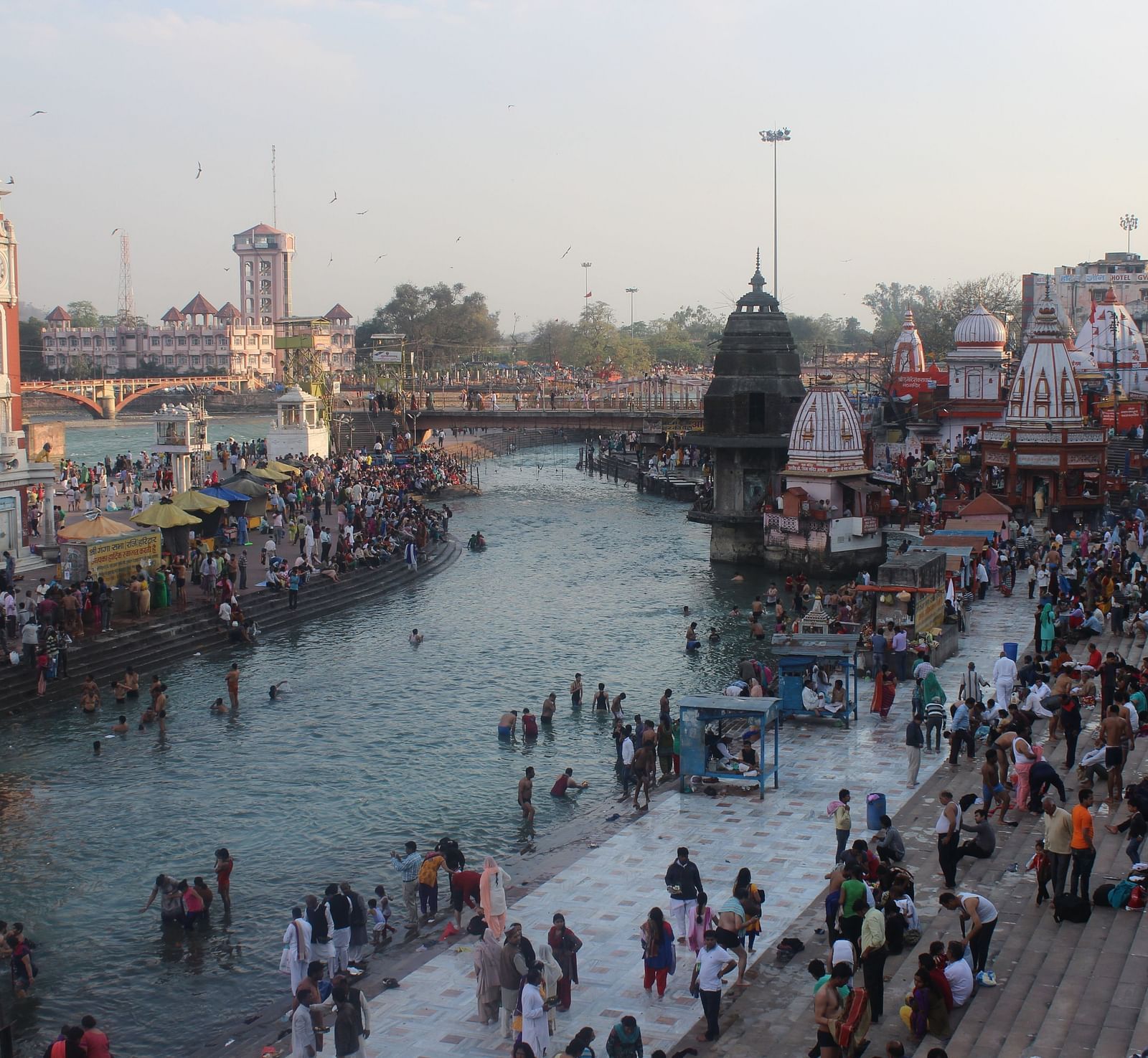 image of a river side pilgrimage site with a lot of devotees on the river bank