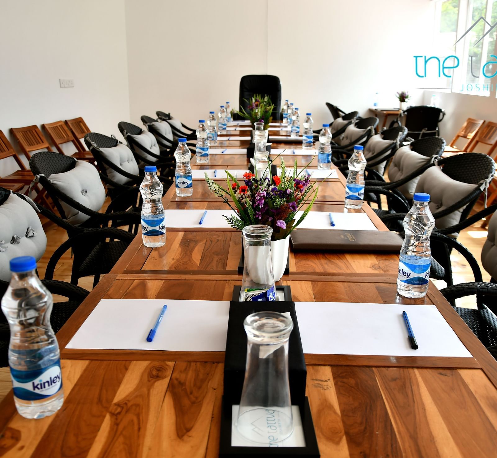front view image of the conference hall featuring the expansive table decorated with flowers and stationery at the tattva, joshimath
