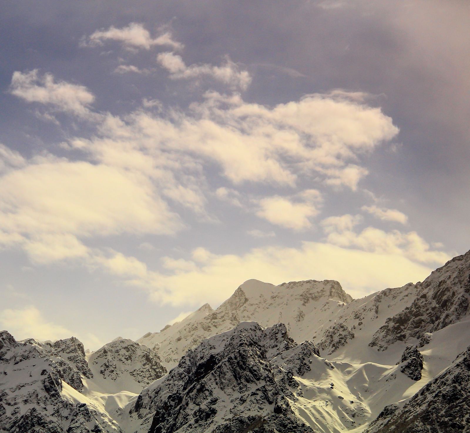 image of a mountain range covered with snow with a beautiful calm sky in the background