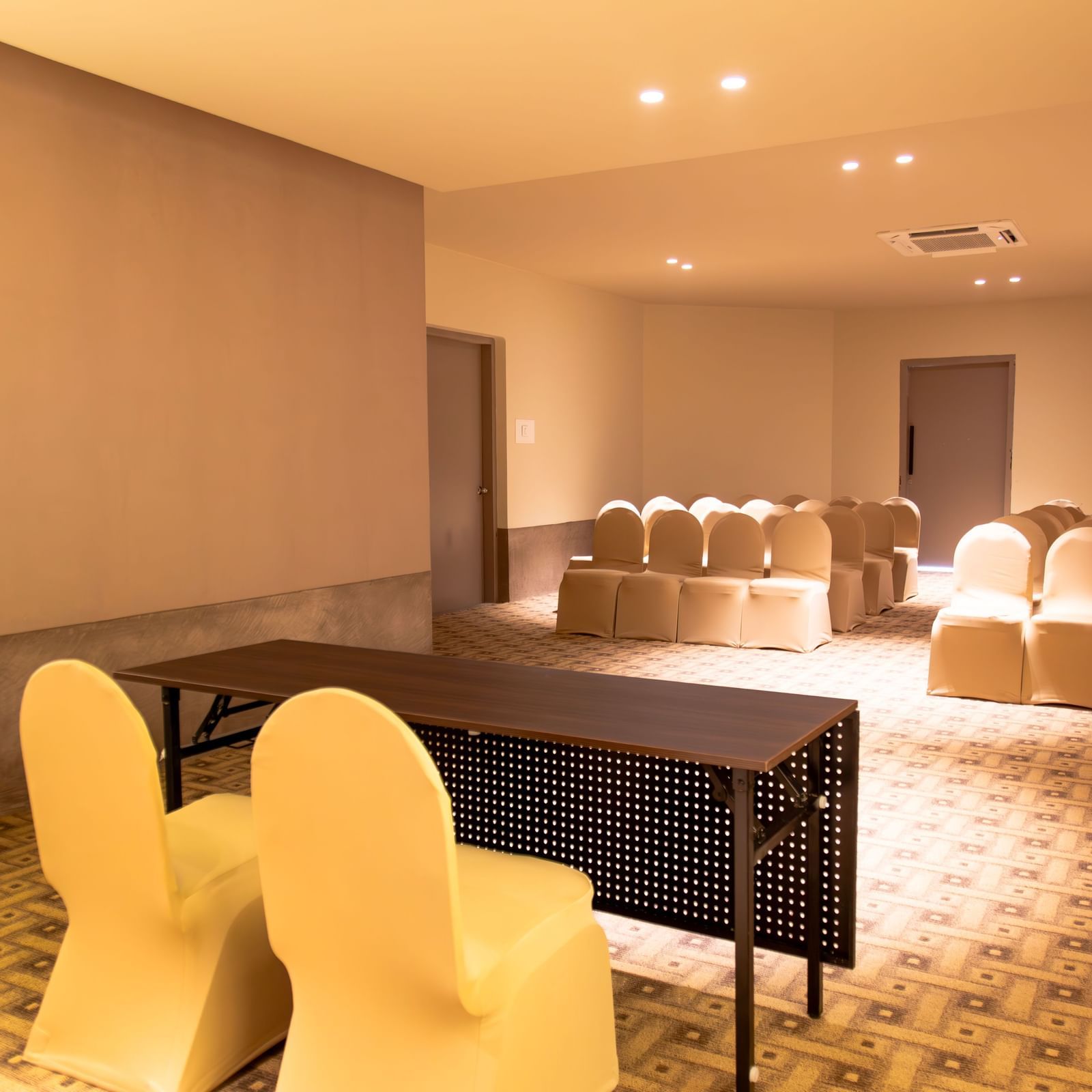  A well-lit conference room at Shilton International, Kochi, with rows of chairs set up for an event, and two tables in front.