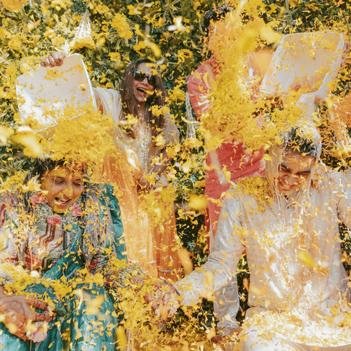 A joyful scene of a bride and groom during their Haldi ceremony, surrounded by vibrant flowers being thrown at them, capturing their happiness and celebration