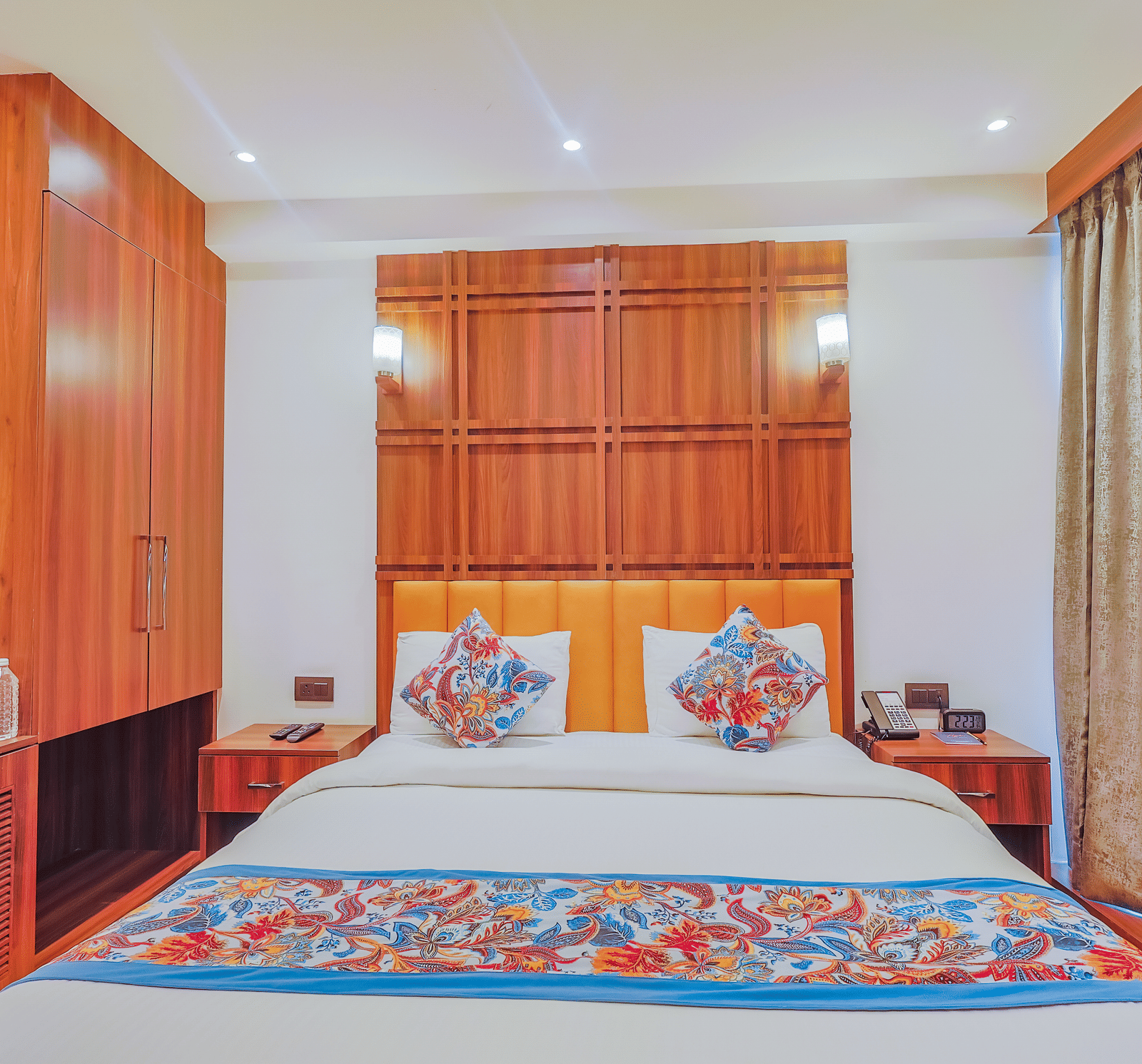 A well-decorated hotel room with a large bed, wooden furniture, and patterned bed linens - Hyphen Business Hotel, Noida