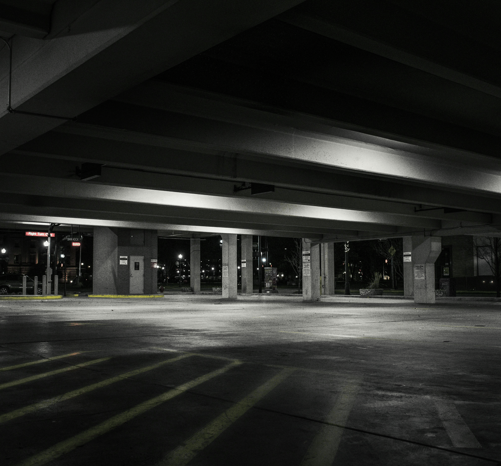 Empty car parking area with lights and pillars in distance.