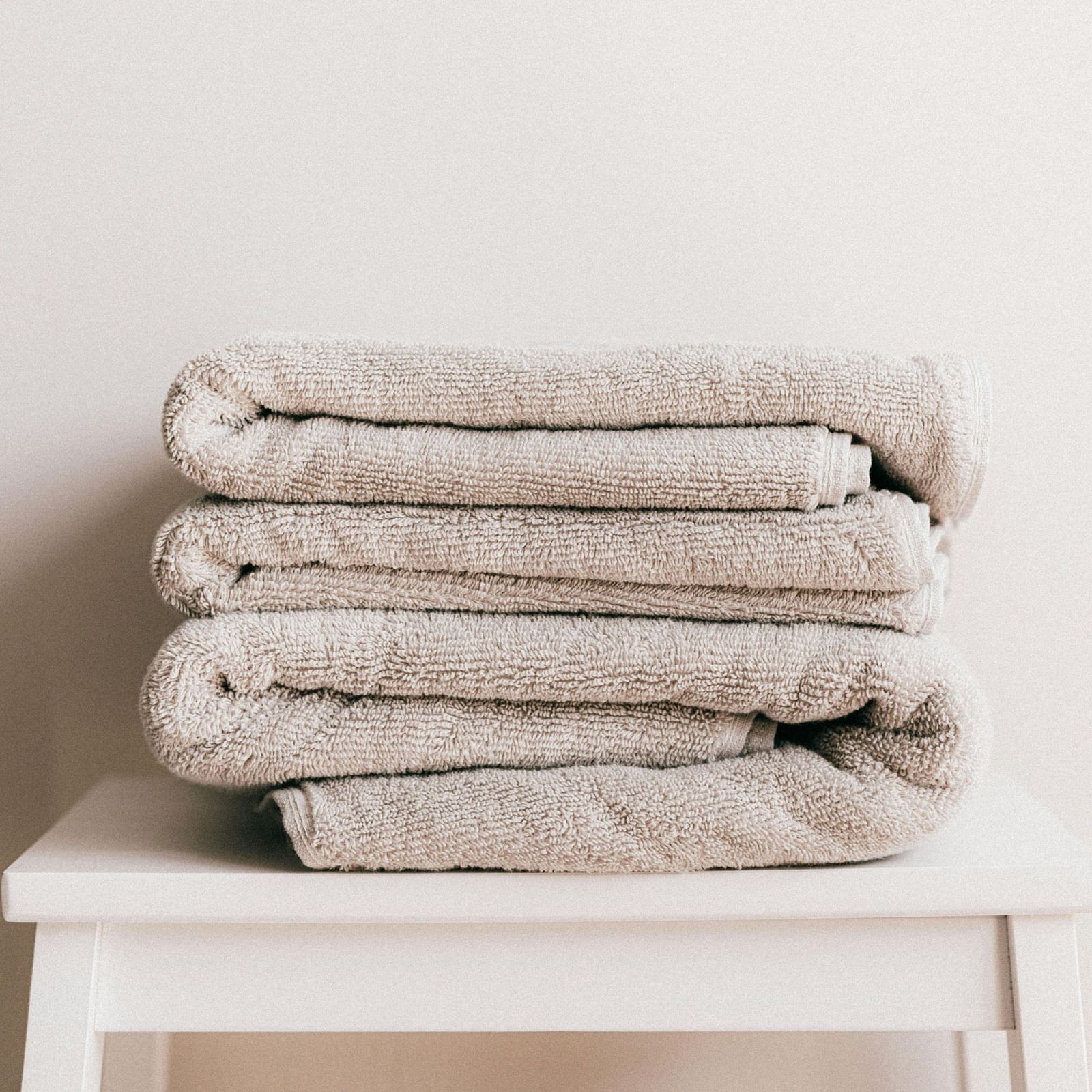 image of a few white coloured towels neatly folded and kept on a stool