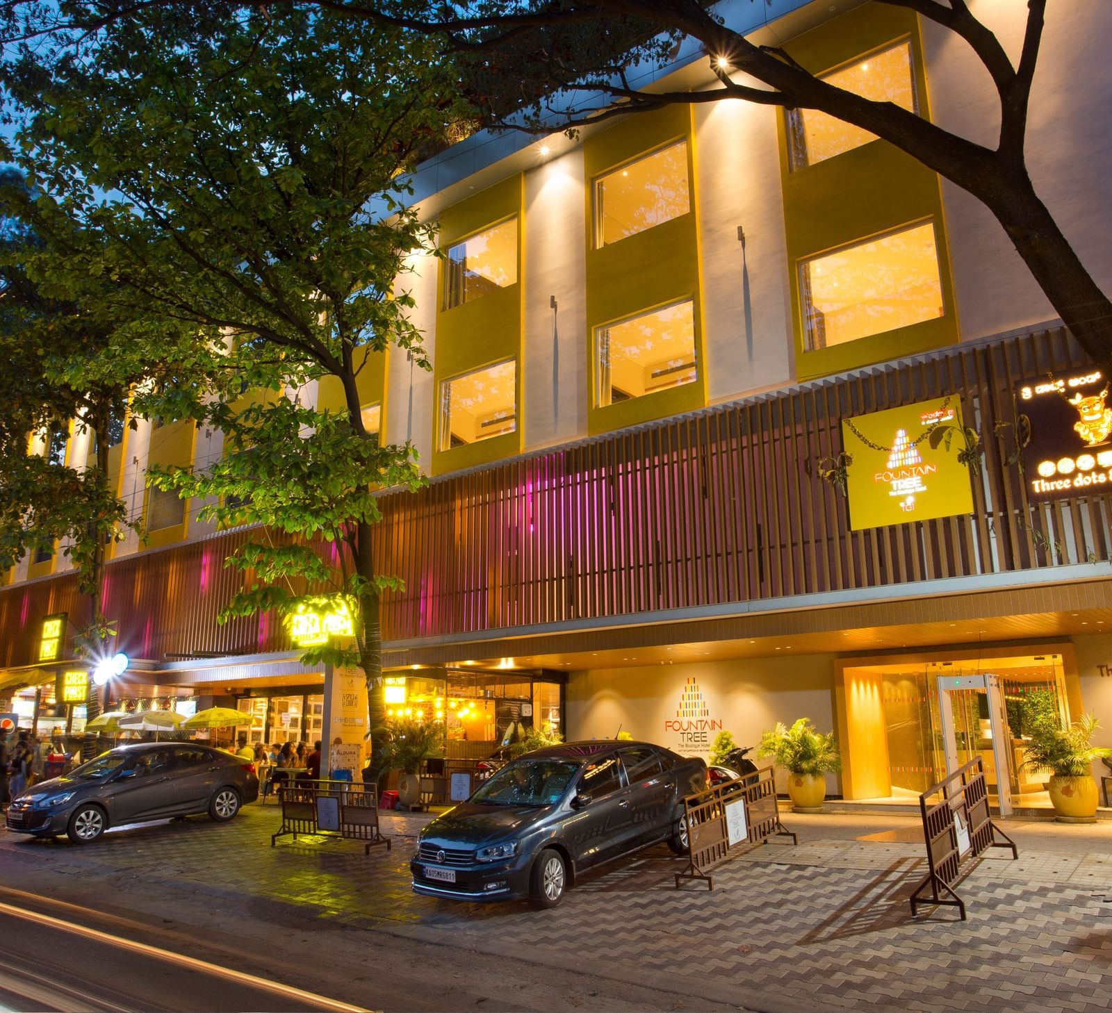 wide view of the facade of the hotel with cars parked outside the front - Hotel Fountain Tree By TGI - JP Nagar, Bangalore