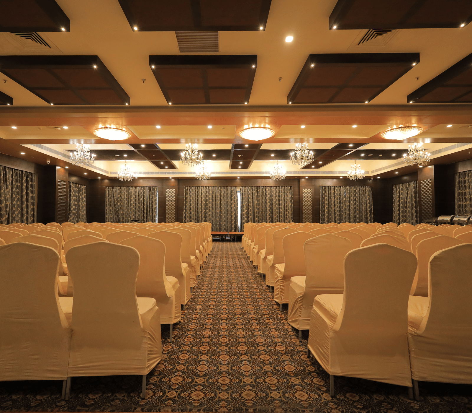 Full view of the Rolse Royse banquet hall with chairs facing towards the stage with a pathway in the middle at Benzz Park, Vellore.