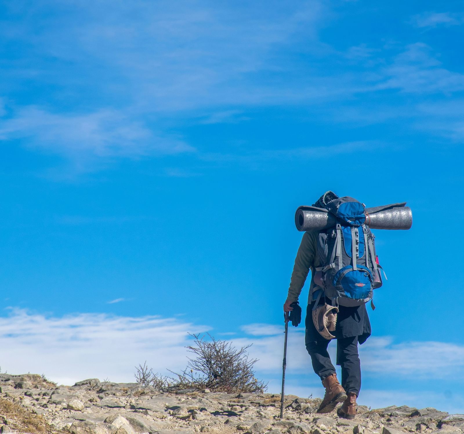 A person trekking with a camera attached to a telephoto lens
