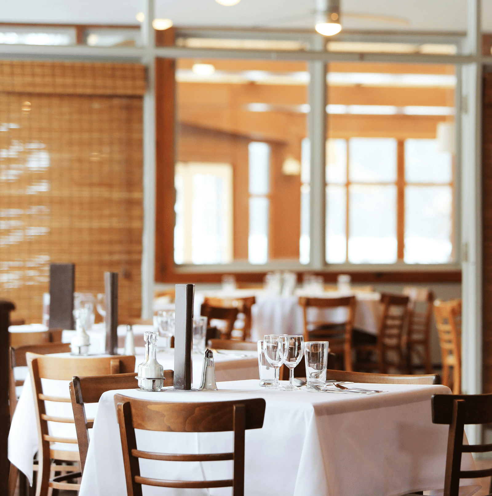 Elegant restaurant interior with neatly set tables, wooden chairs, and soft ambient lighting.