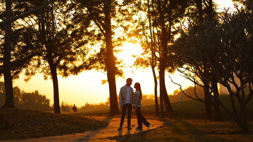 a couple standing on a gold course during sunset - Karma Lakelands.