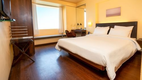 A front view off the suite  with plushy bed and a window with a wall painting  at Marasa Sarovar Portico, Rajkot