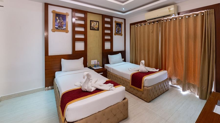 Comfort-focused twin bed setup with a muted golden curtain backdrop, warm lighting, and minimal clutter, providing a peaceful atmosphere for longer stays.