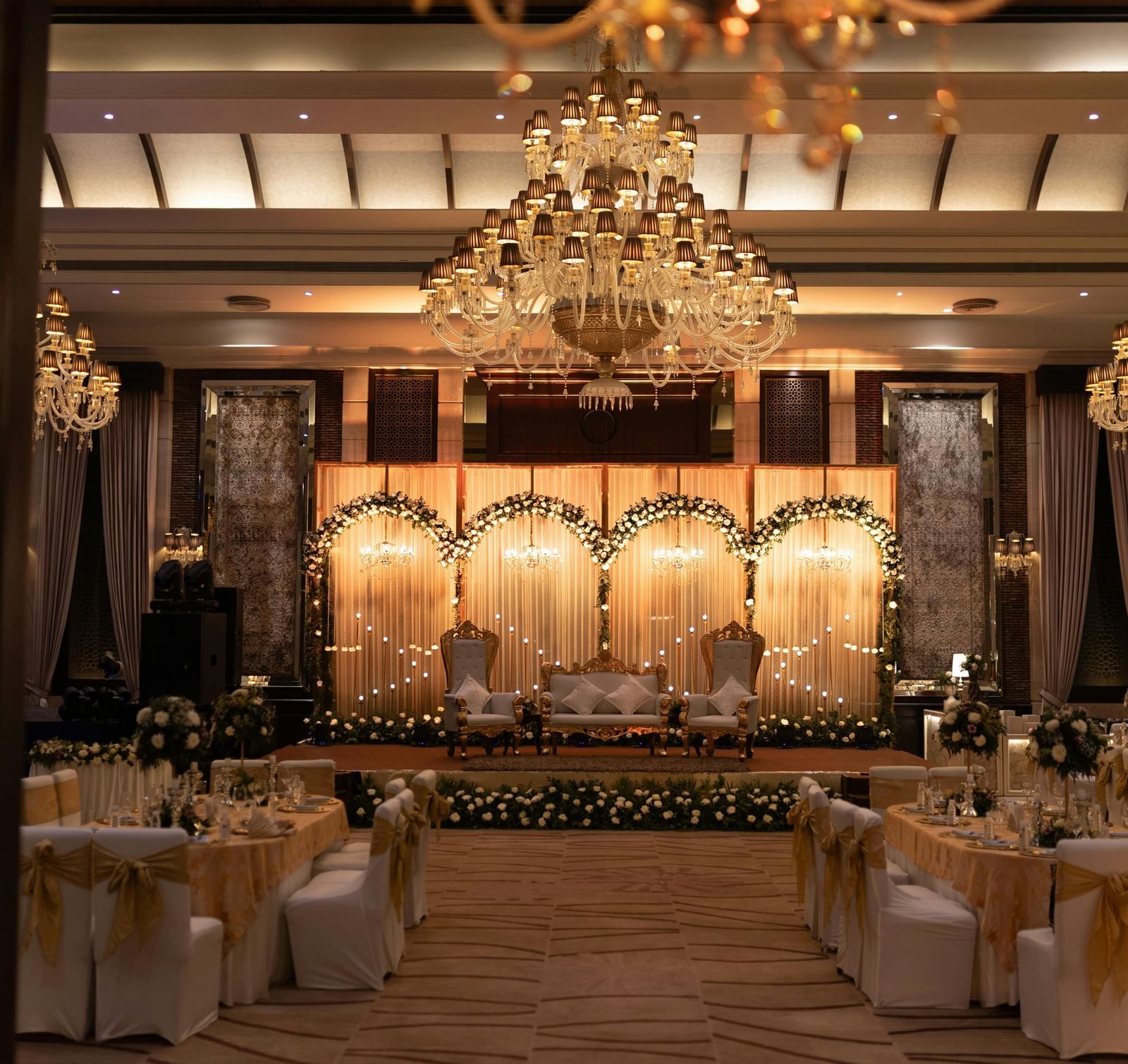 A luxurious reception area, richly decorated with warm lighting, chandeliers, and classical styling
