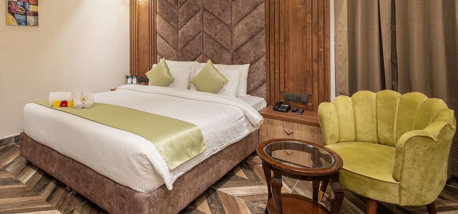 Image of Deluxe Room at DLS Grand Luxotica, Dehradun featuring a plush bed with a sitting space next to it by the window 