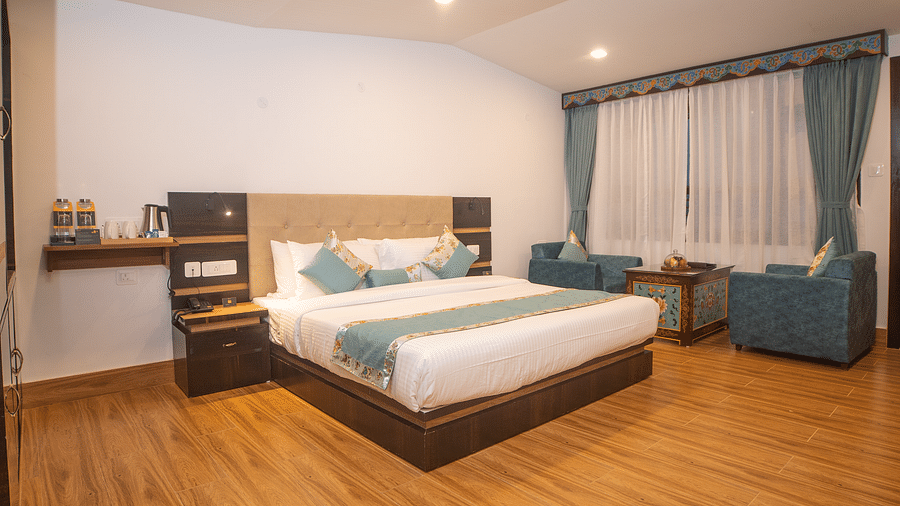Elegant guest room at Voyage Glenz Resort with plush bedding, sofa, and warm lighting.