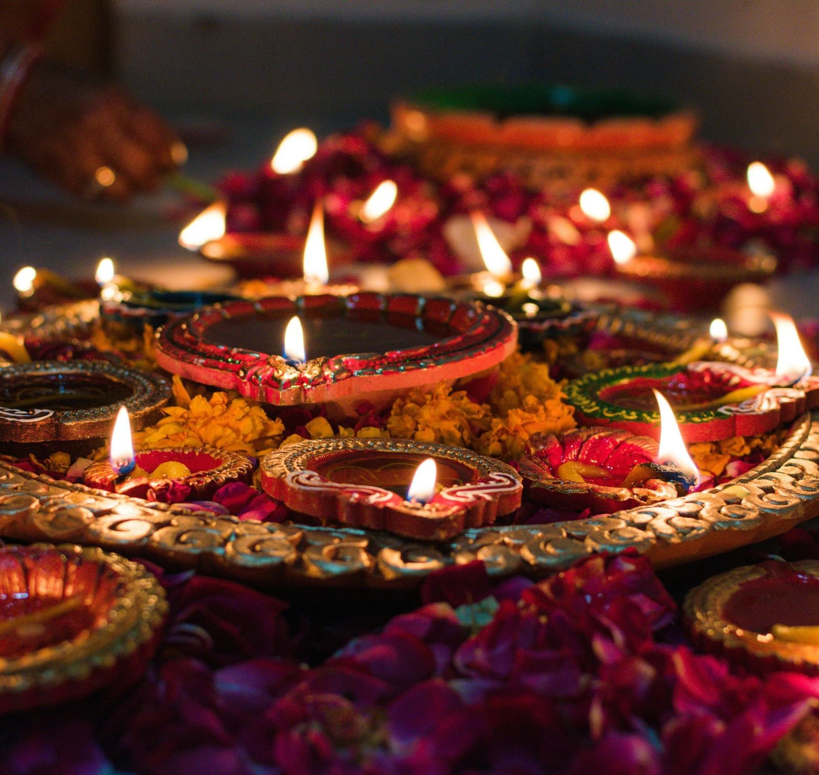 A close up shot of a plate carrying several earthen lamps surrounded by flower petals.