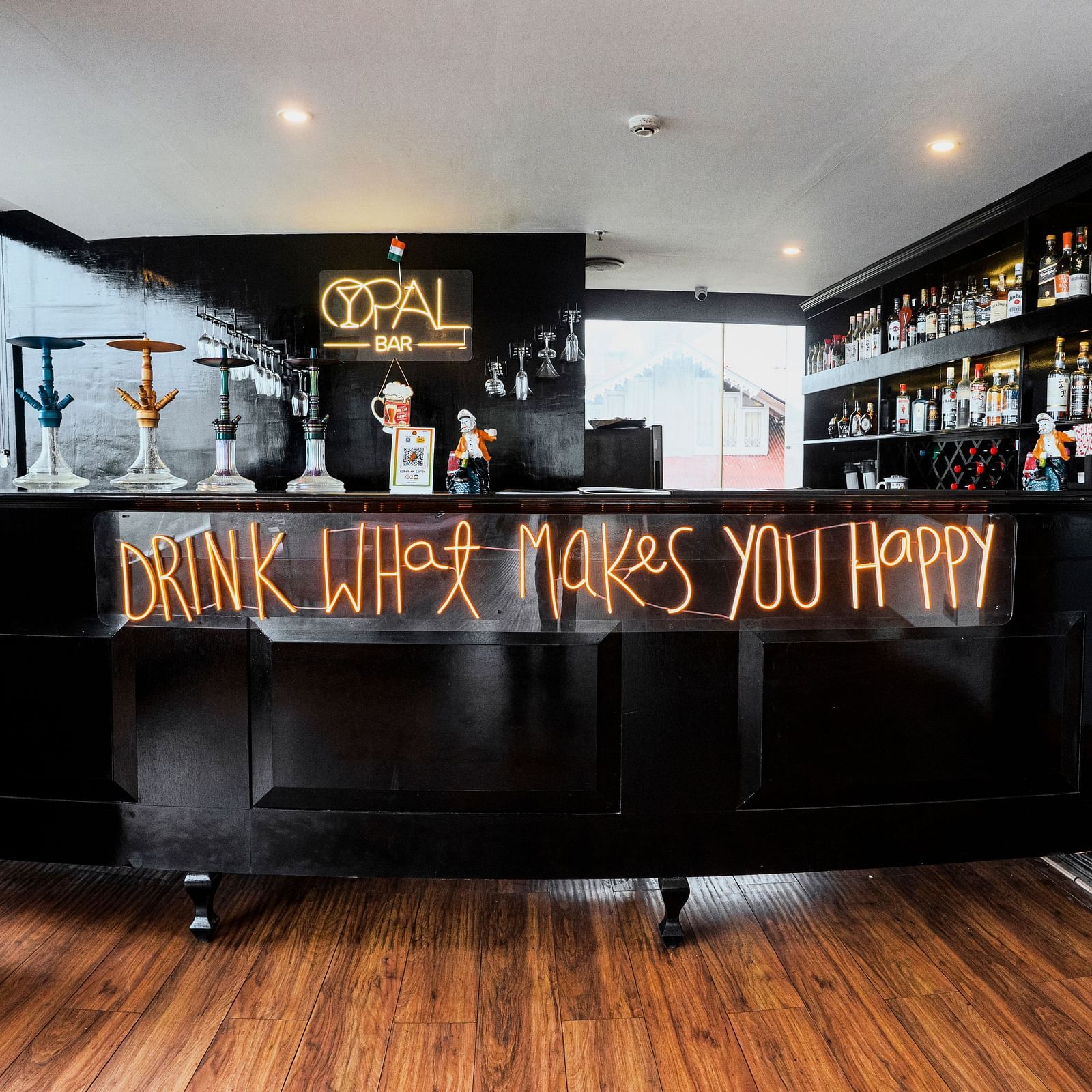 A wide shot of a dark bar counter at Orsino Spa Resort with shelves filled with various items, illuminated by warm lighting.