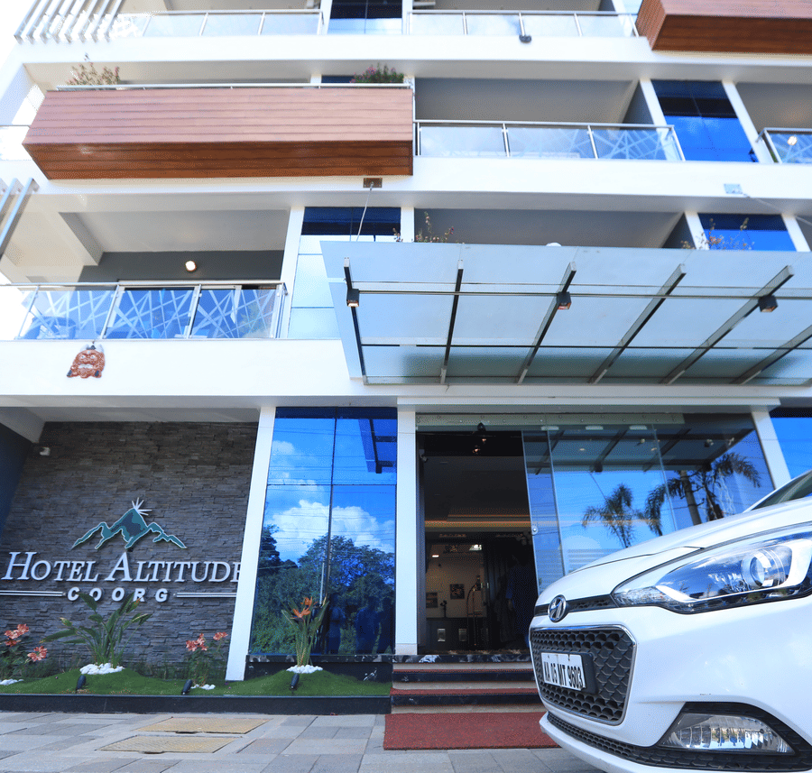 Facade of Hotel Altitude with a car parked in front of it.