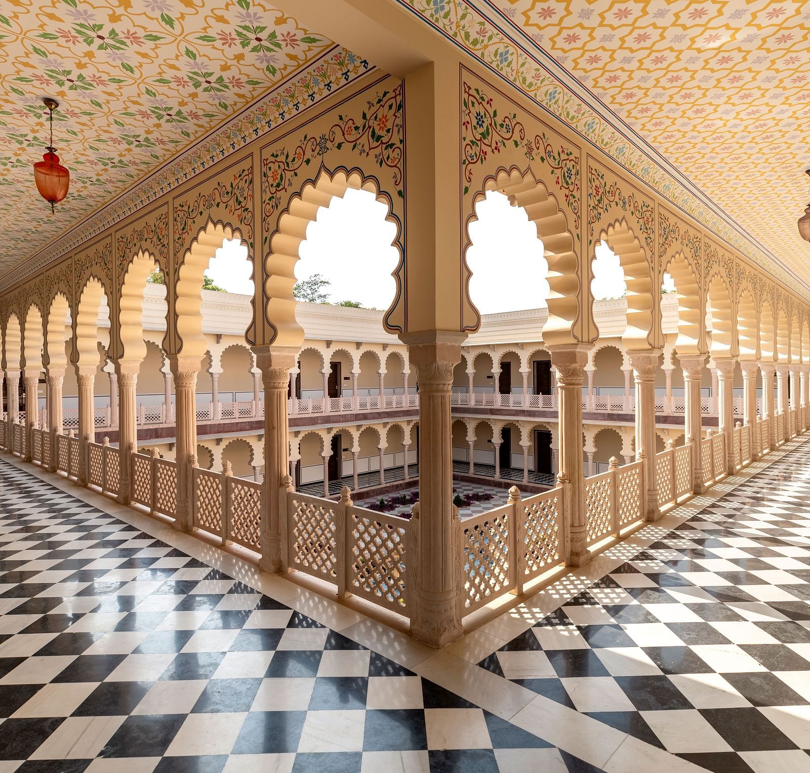 Ornate palace corridor with arches and black-and-white flooring