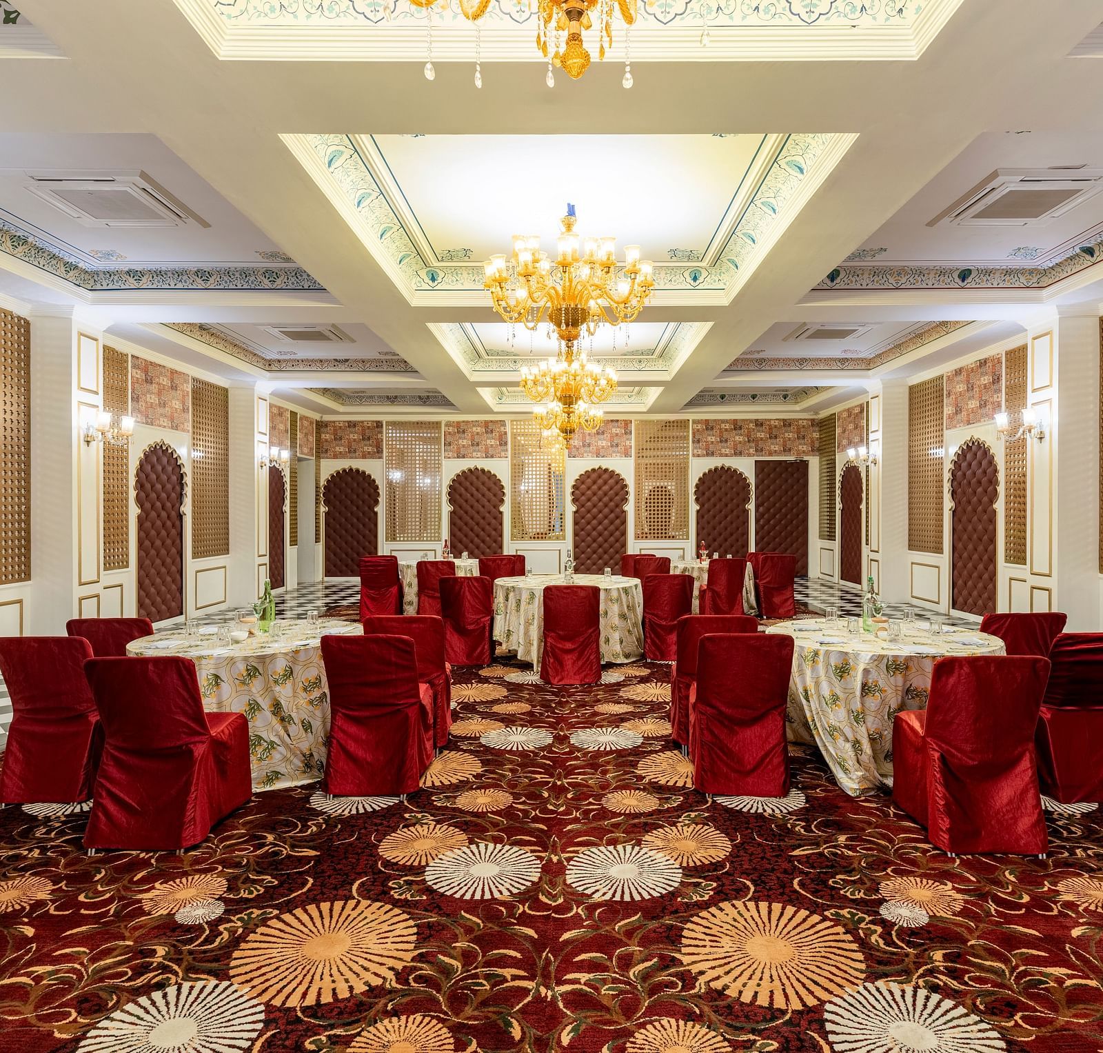 Luxurious banquet hall with red chairs and ornate ceiling at Kesar Bagh Palace.