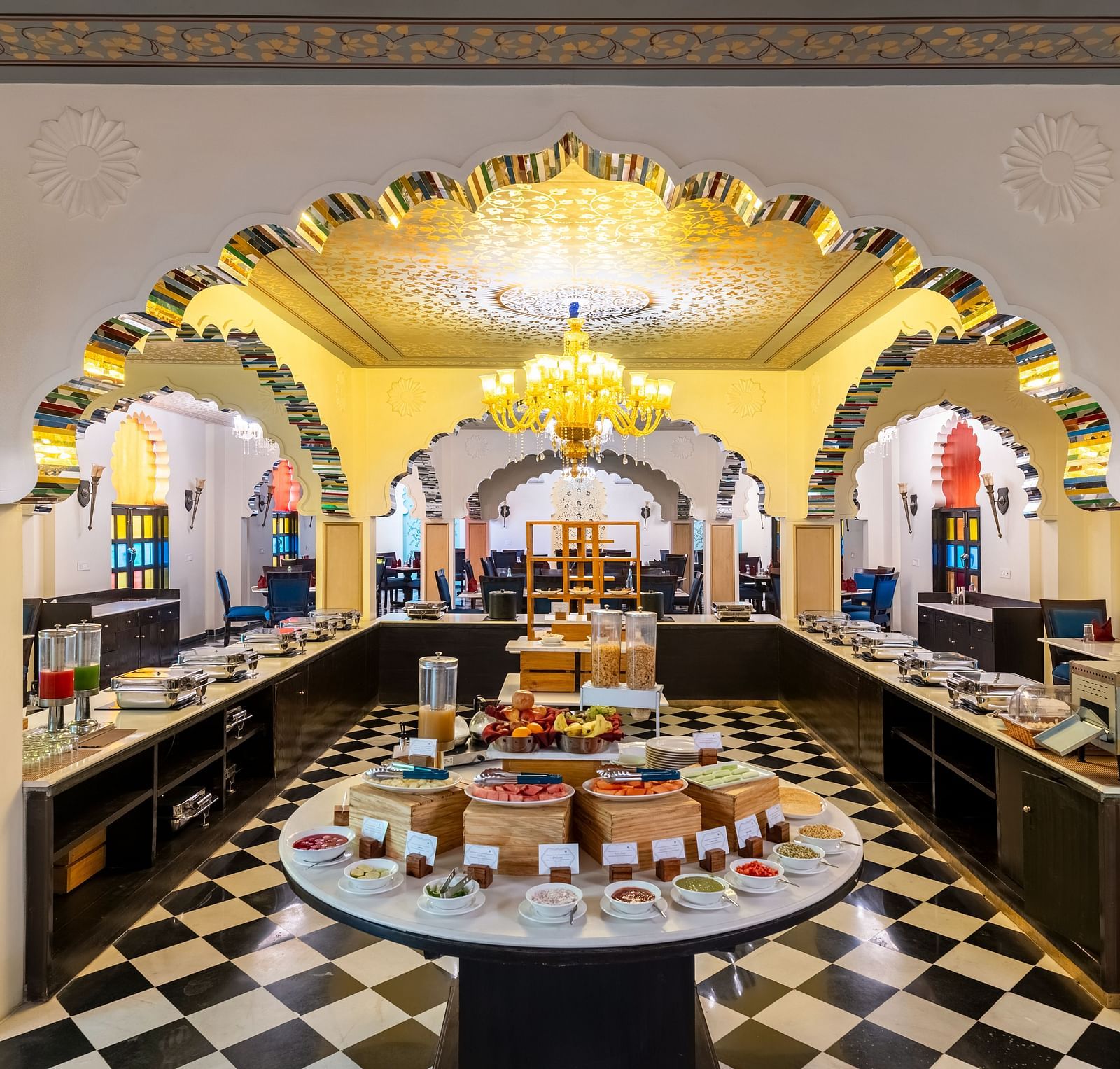 Lavish buffet dining area with black-and-white flooring and chandeliers at Kesar Bagh Palace.