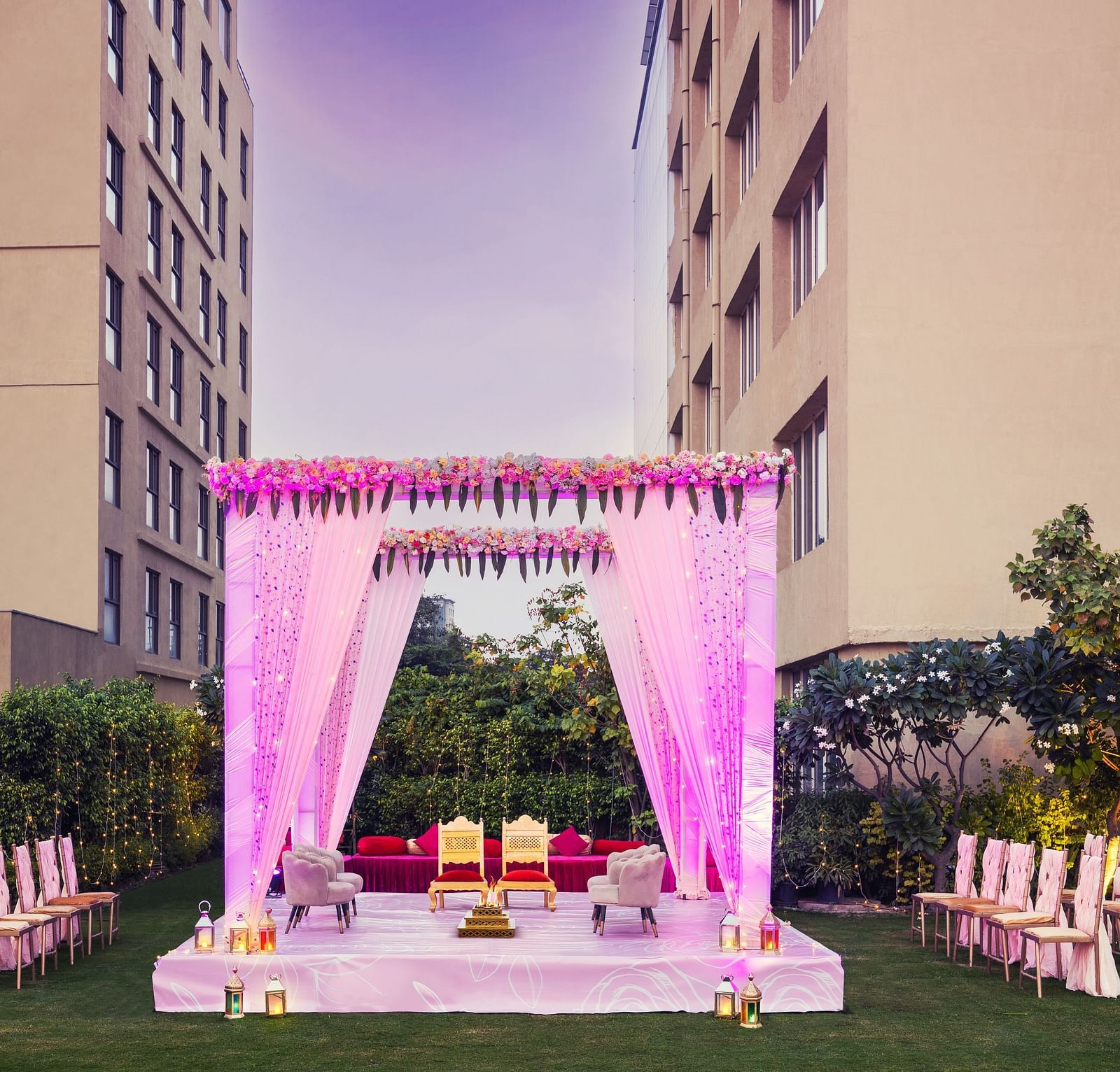 a stage set with two chairs and a canopy above and a group of chairs lined up on either side of the stage - The Hideaway Banquets & Lawns, Greater Noida