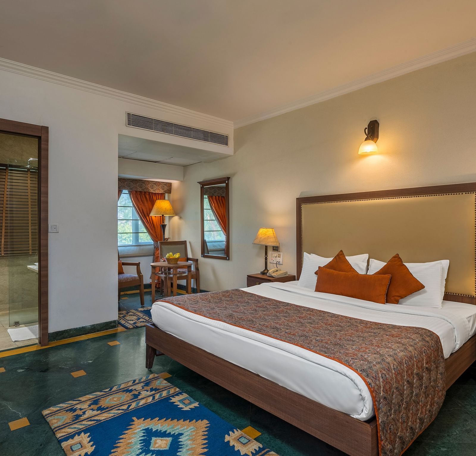 A bedroom with a large bed with side drawers placed on both sides of the bed, with an overhead lamp and side lamps - The Manor, Kashipur