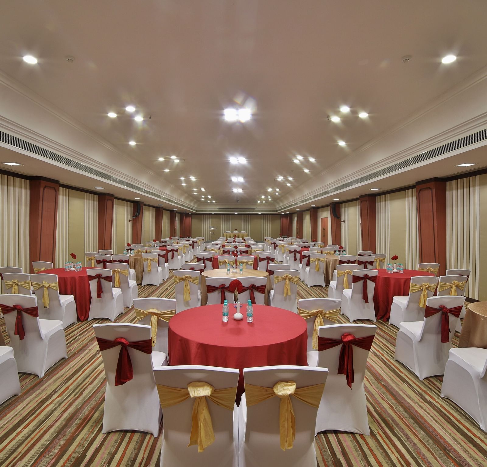  Seating arrangement in Terrace Hall A grand hotel suite with an opulent red and white decor, large bed, and seating area, reflecting a traditional style at Sitara Luxury Hotel in Hyderabad near Ramoji Film City.