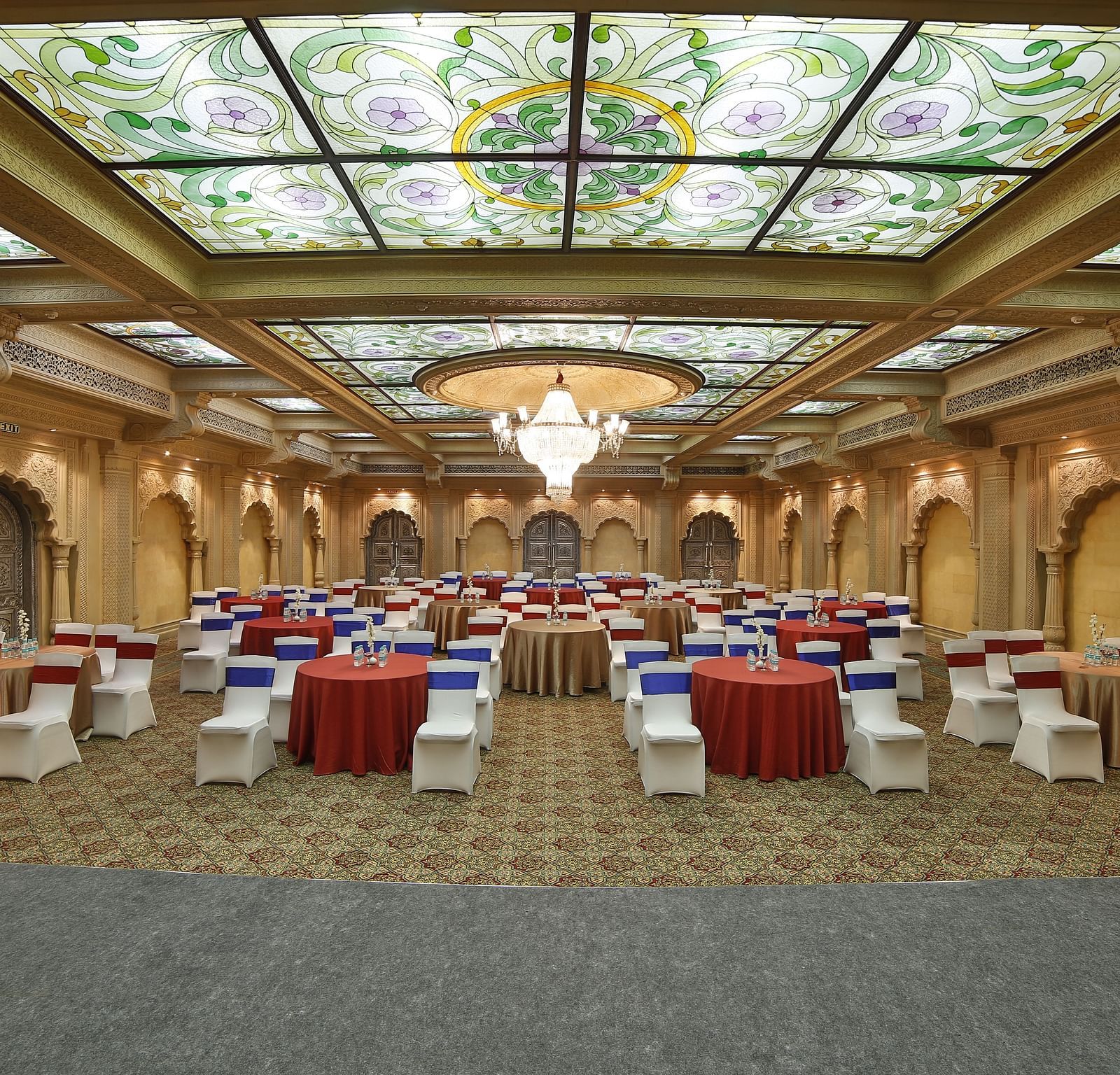  Seating arrangement in Taj Mahal Hall A grand hotel suite with an opulent red and white decor, large bed, and seating area, reflecting a traditional style at Sitara Luxury Hotel in Hyderabad near Ramoji Film City.