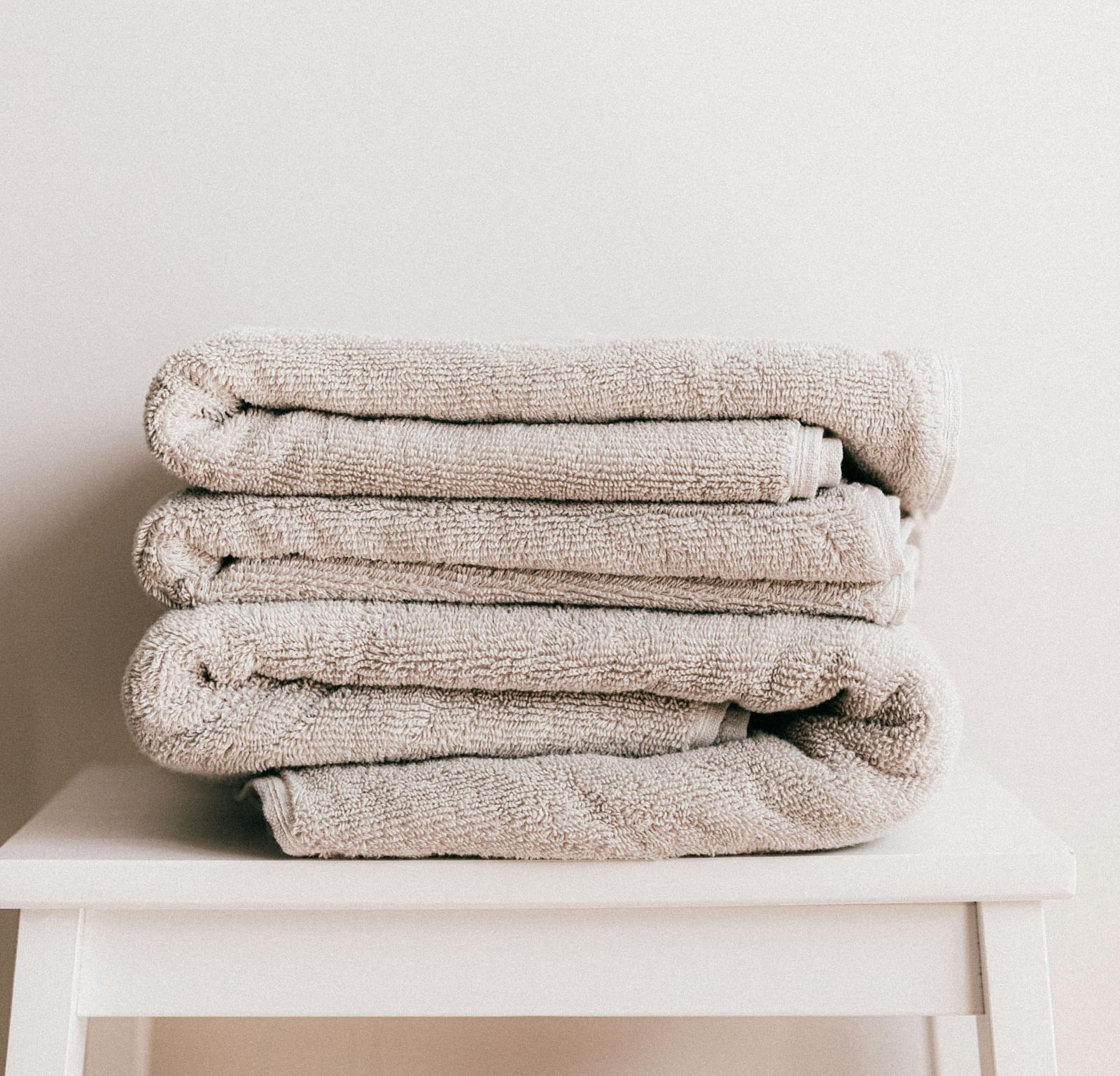 A few white coloured towels neatly folded and kept on a stool.