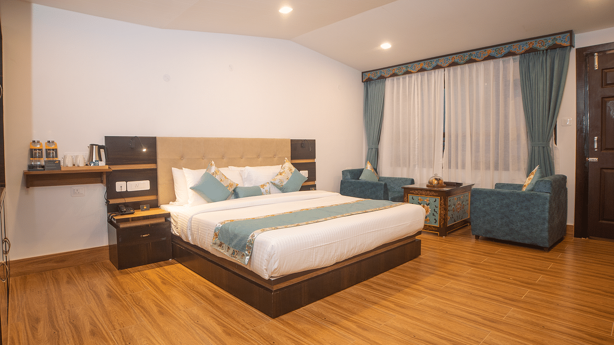 Elegant guest room at Voyage Glenz Resort with plush bedding, sofa, and warm lighting.