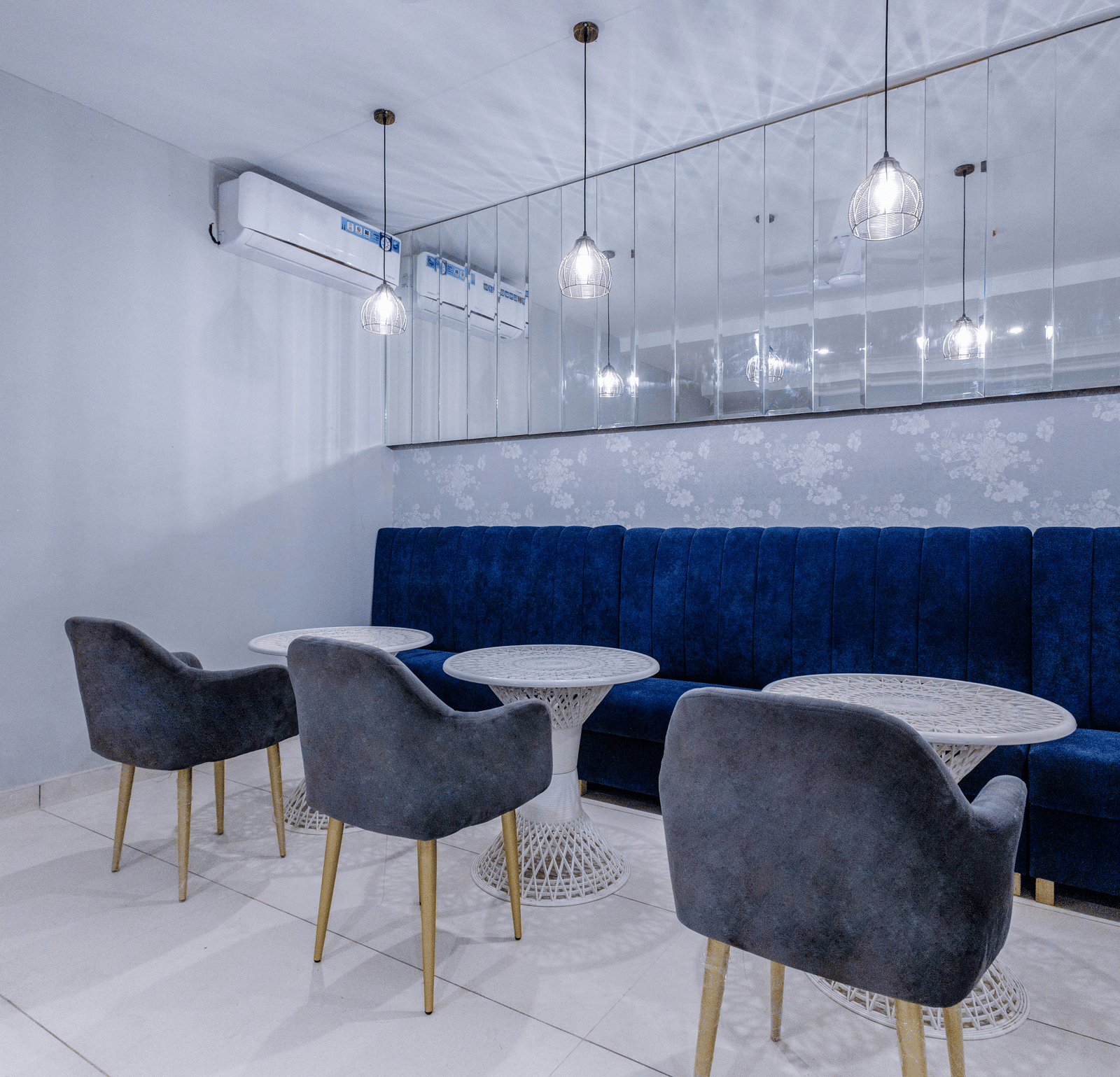 Corner view shot of the restaurant with three round tables with a huge blue couch in front of it - Hotel Downtown17, Chandigarh.